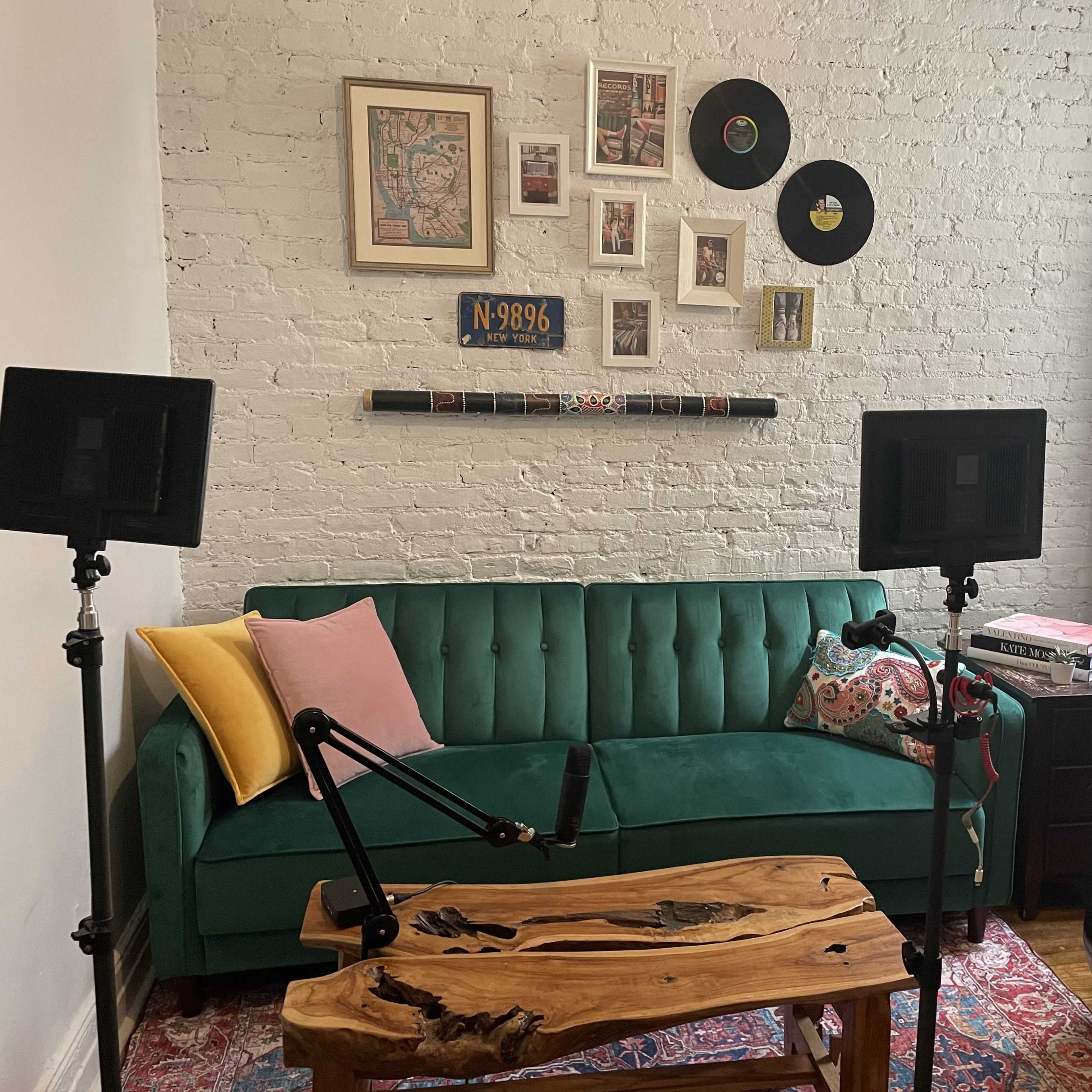 A cozy living room with a green sofa, a wooden coffee table, and wall decorations, including framed artwork and vinyl records.