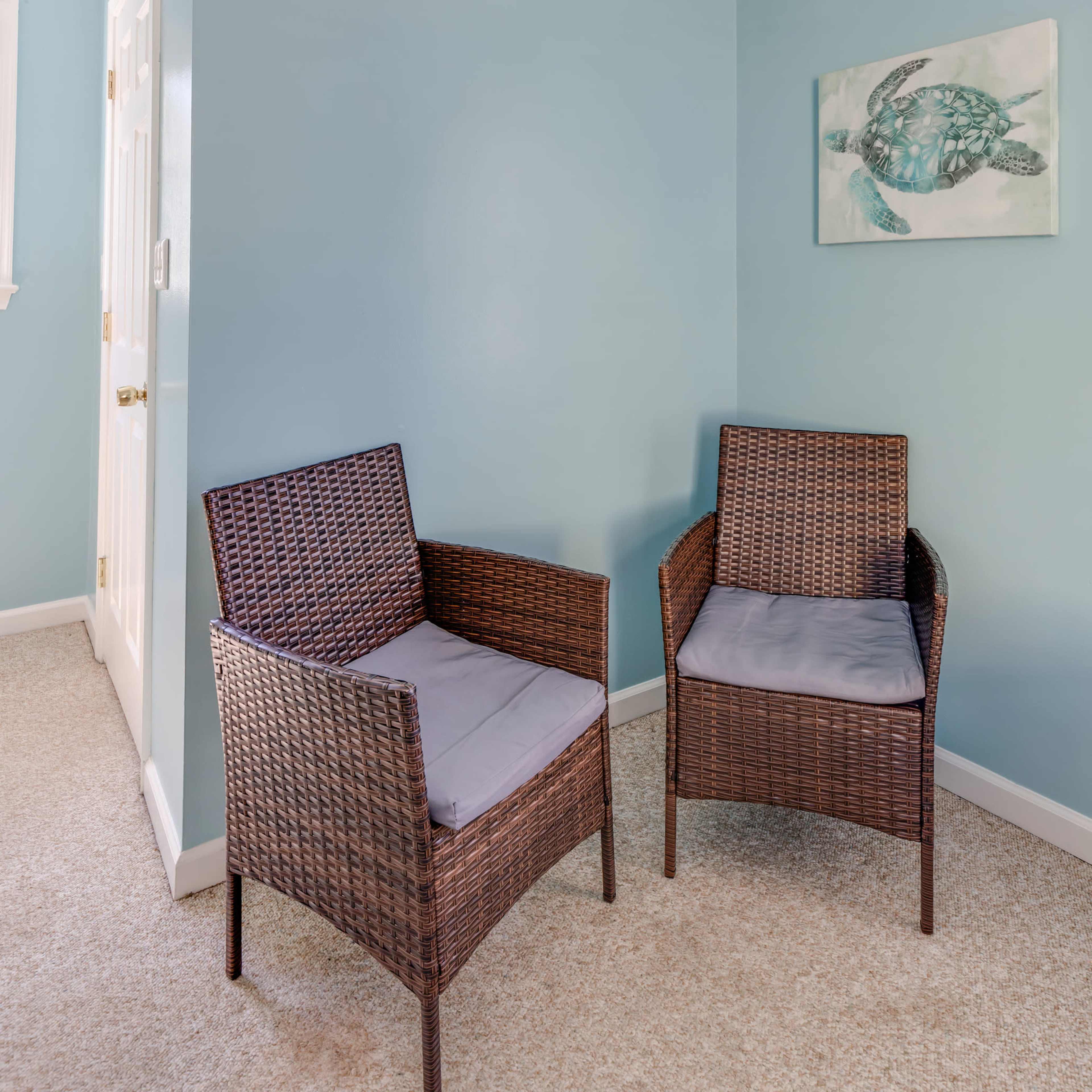 A corner of a room with two wicker chairs and a light blue wall featuring a painting of a turtle.