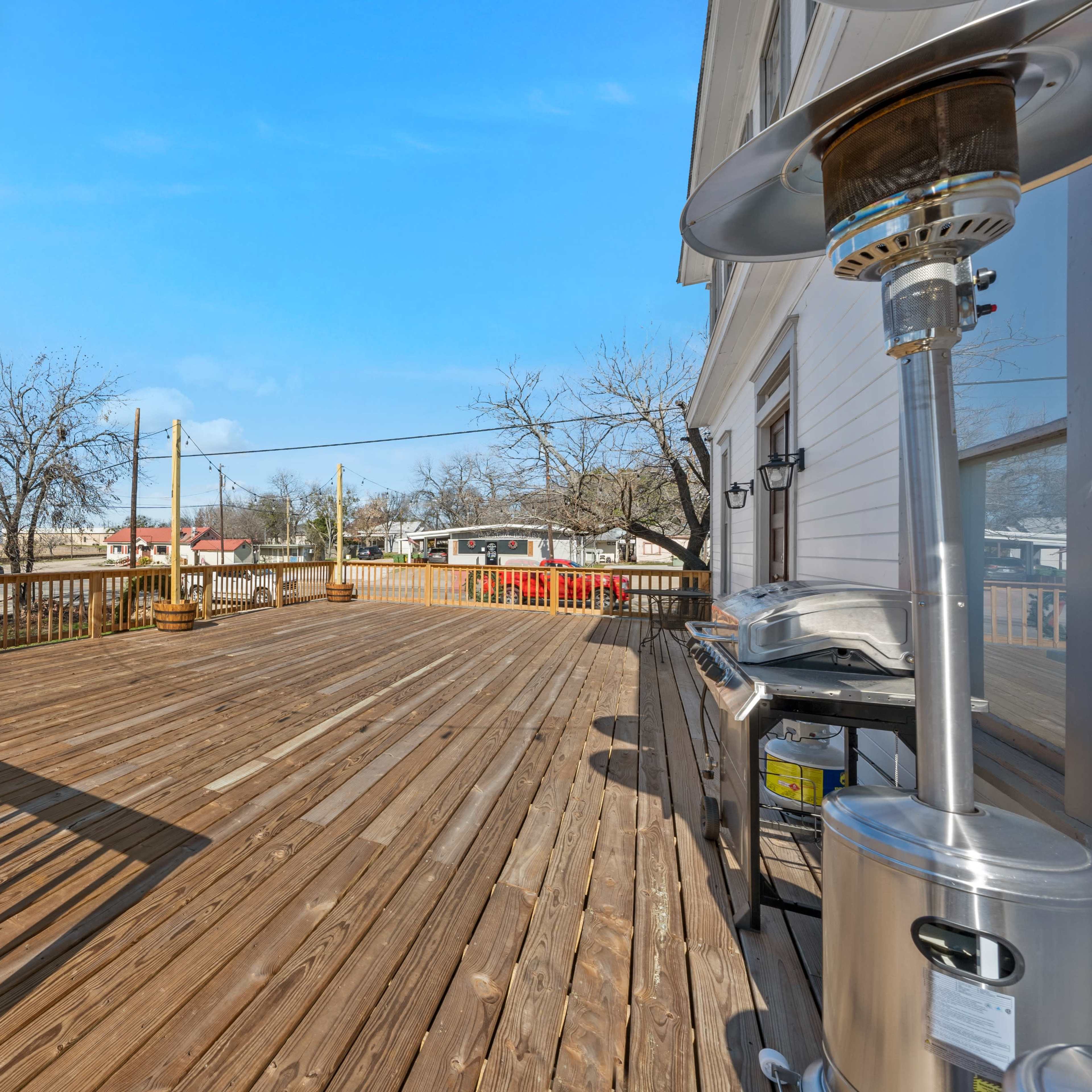A wooden deck with patio lights, a grill, and a clear blue sky in the background.