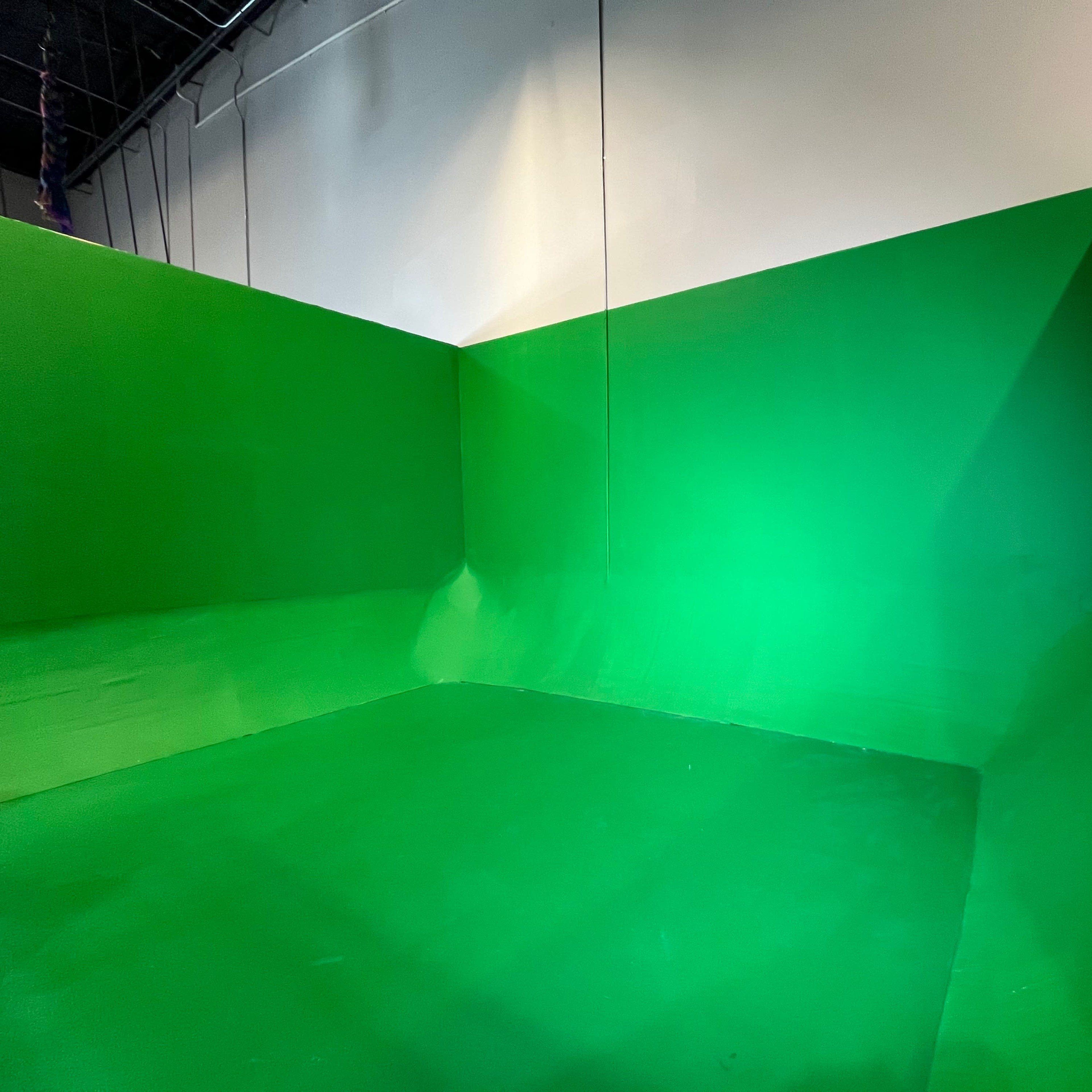 A green room with walls and a floor painted entirely in green, designed for chroma keying.