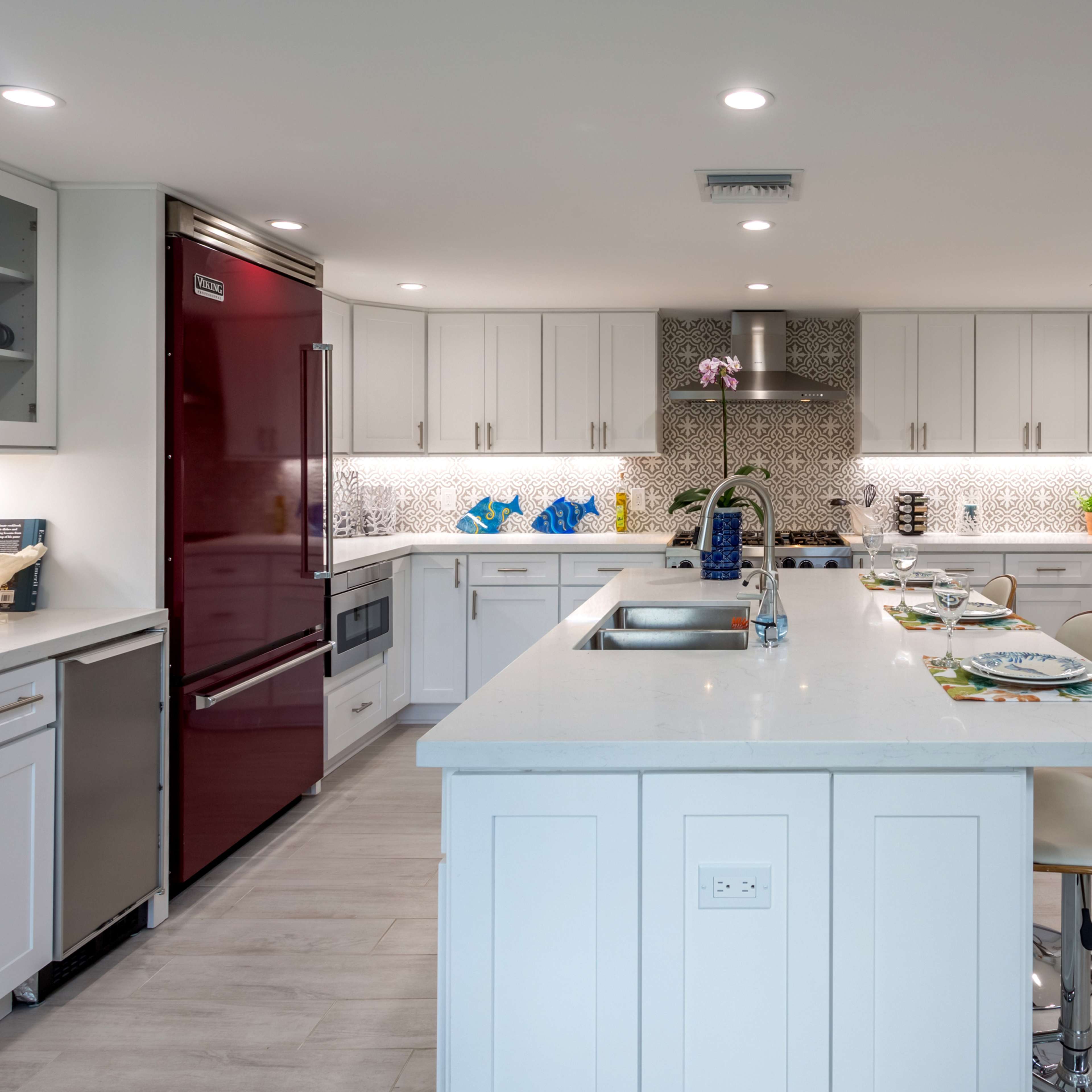 A modern kitchen with stainless steel appliances, white cabinetry, and a central island featuring bar stools.