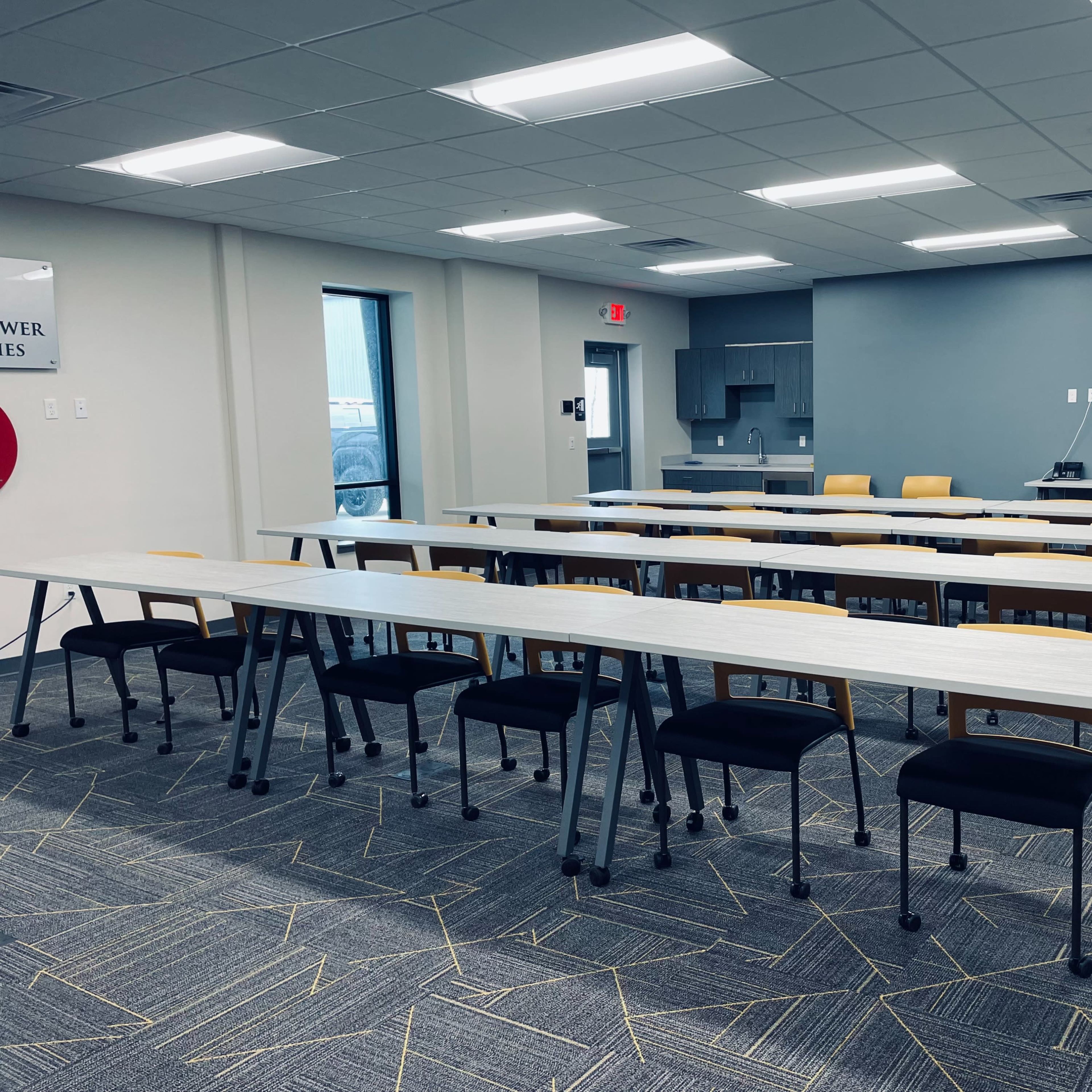 A modern classroom setup with several rows of tables and chairs arranged neatly in a well-lit space.