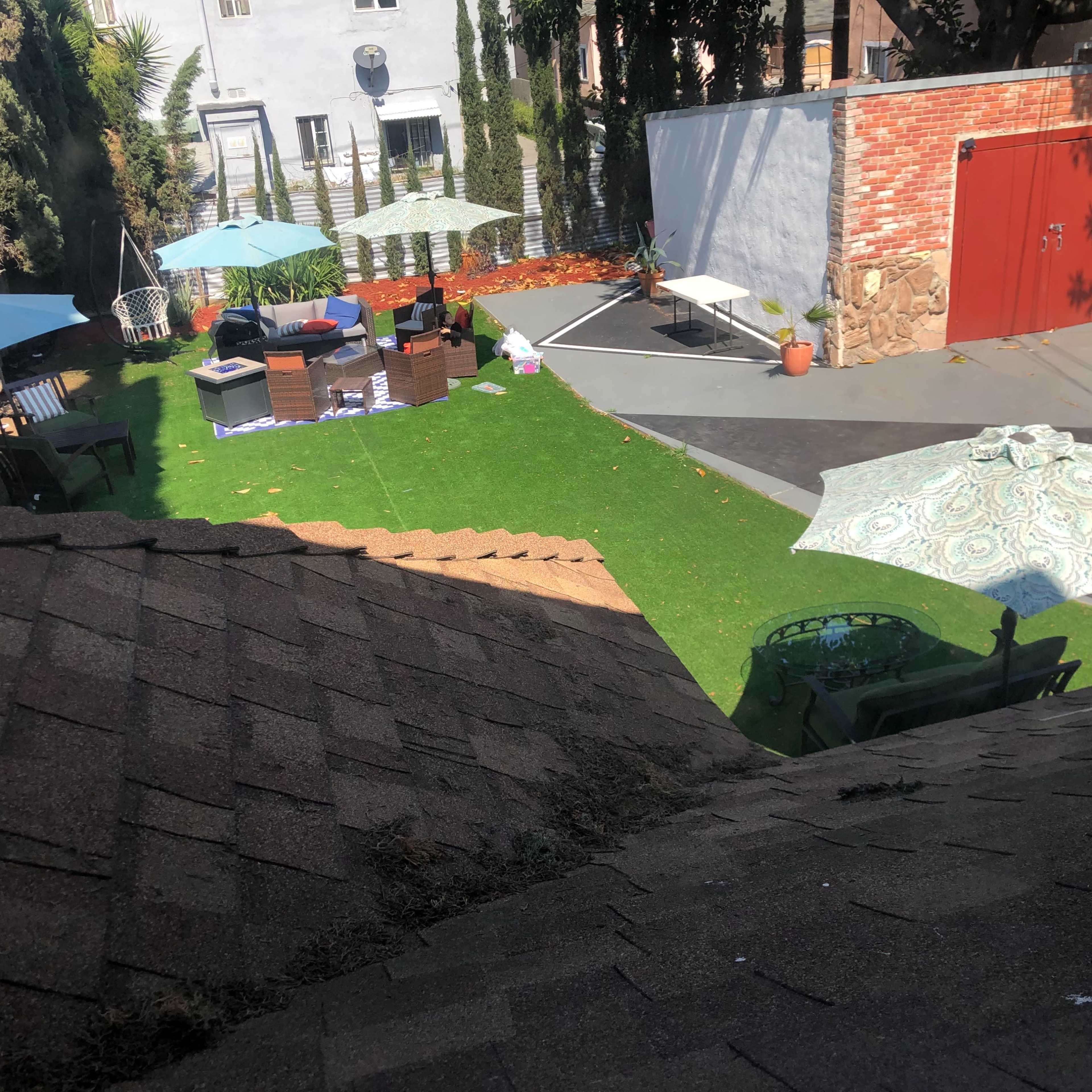 A backyard featuring artificial grass, patio furniture, and several umbrellas providing shade.