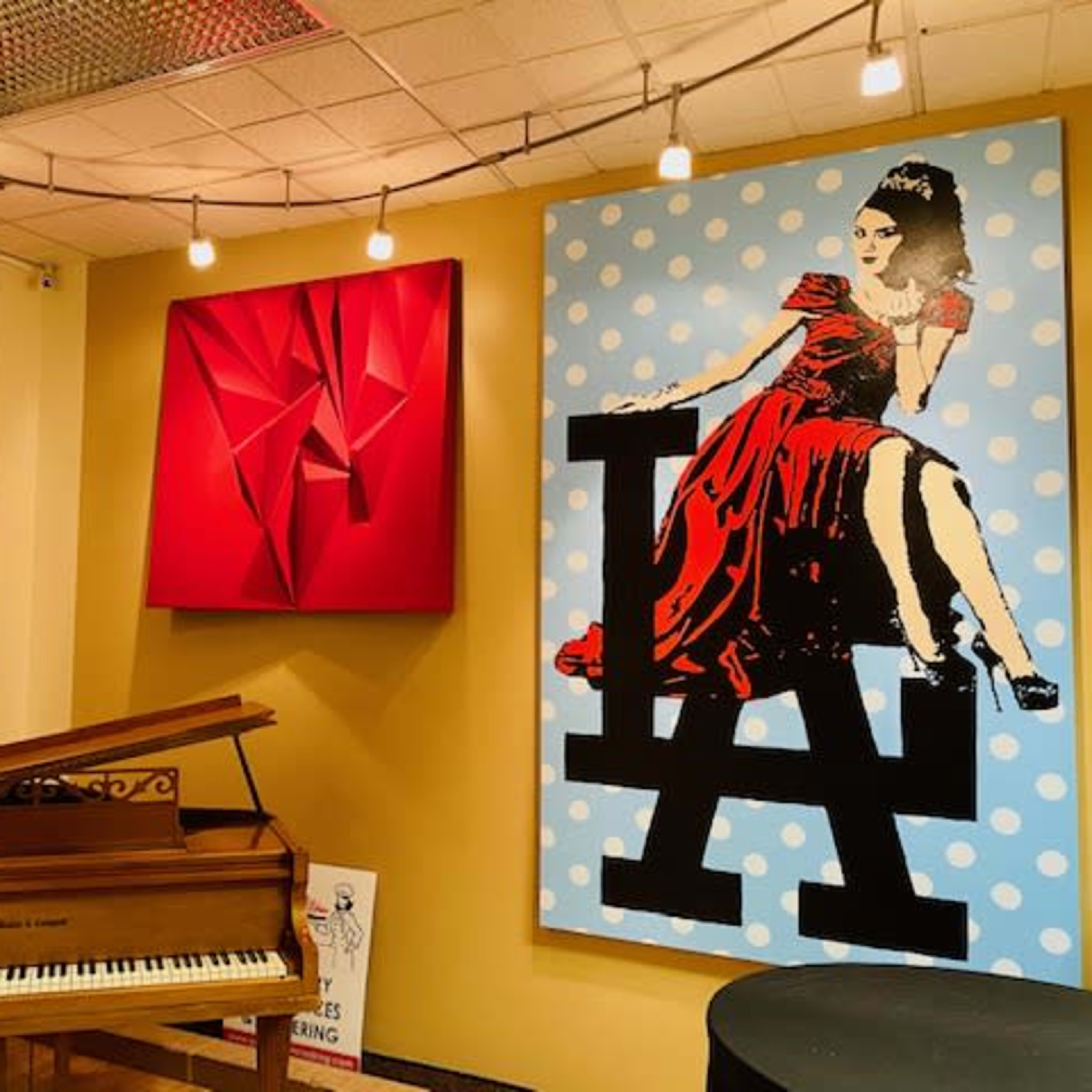 A music room featuring a grand piano, vibrant wall art, and decorative lighting.