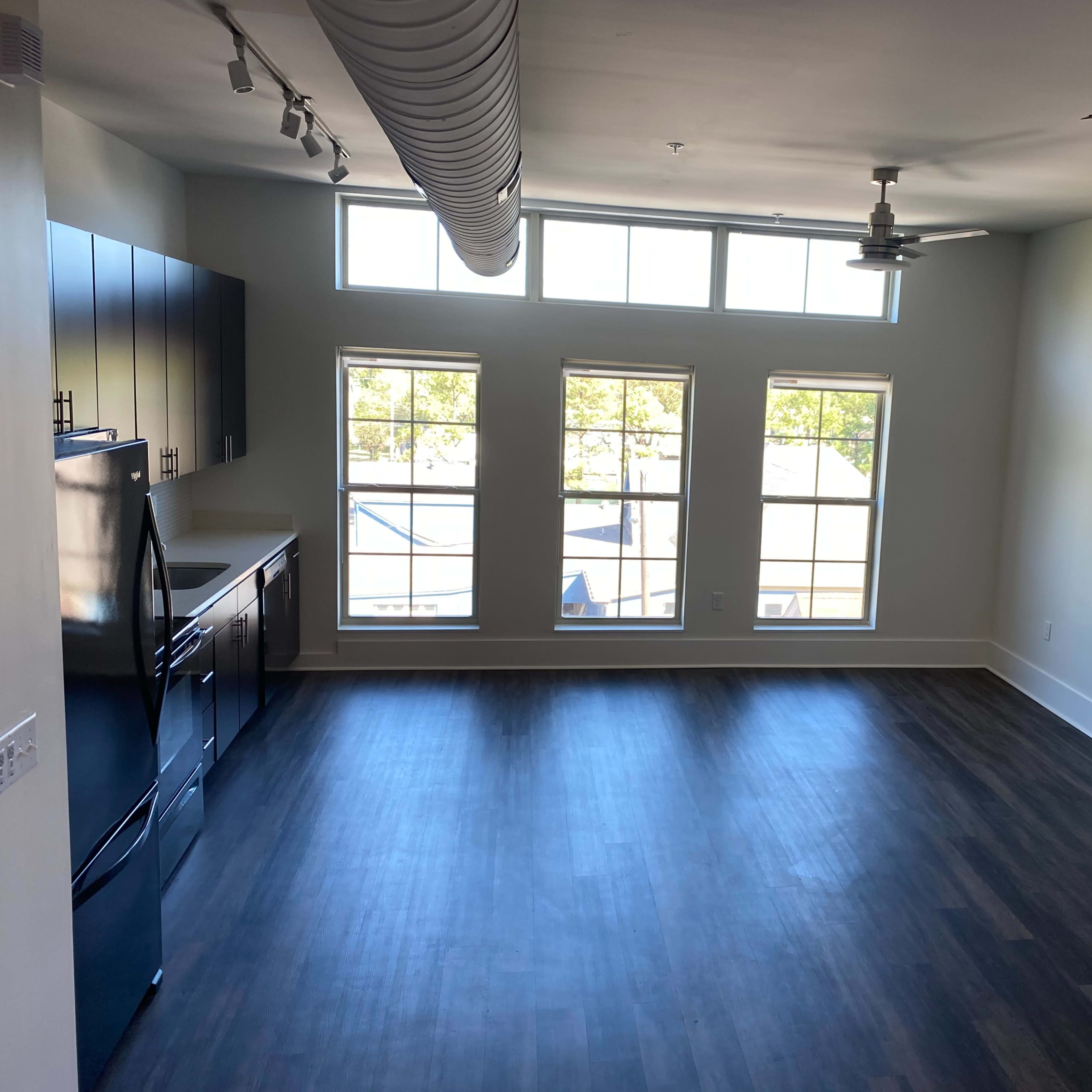 A spacious room features large windows and a kitchen area with modern appliances.