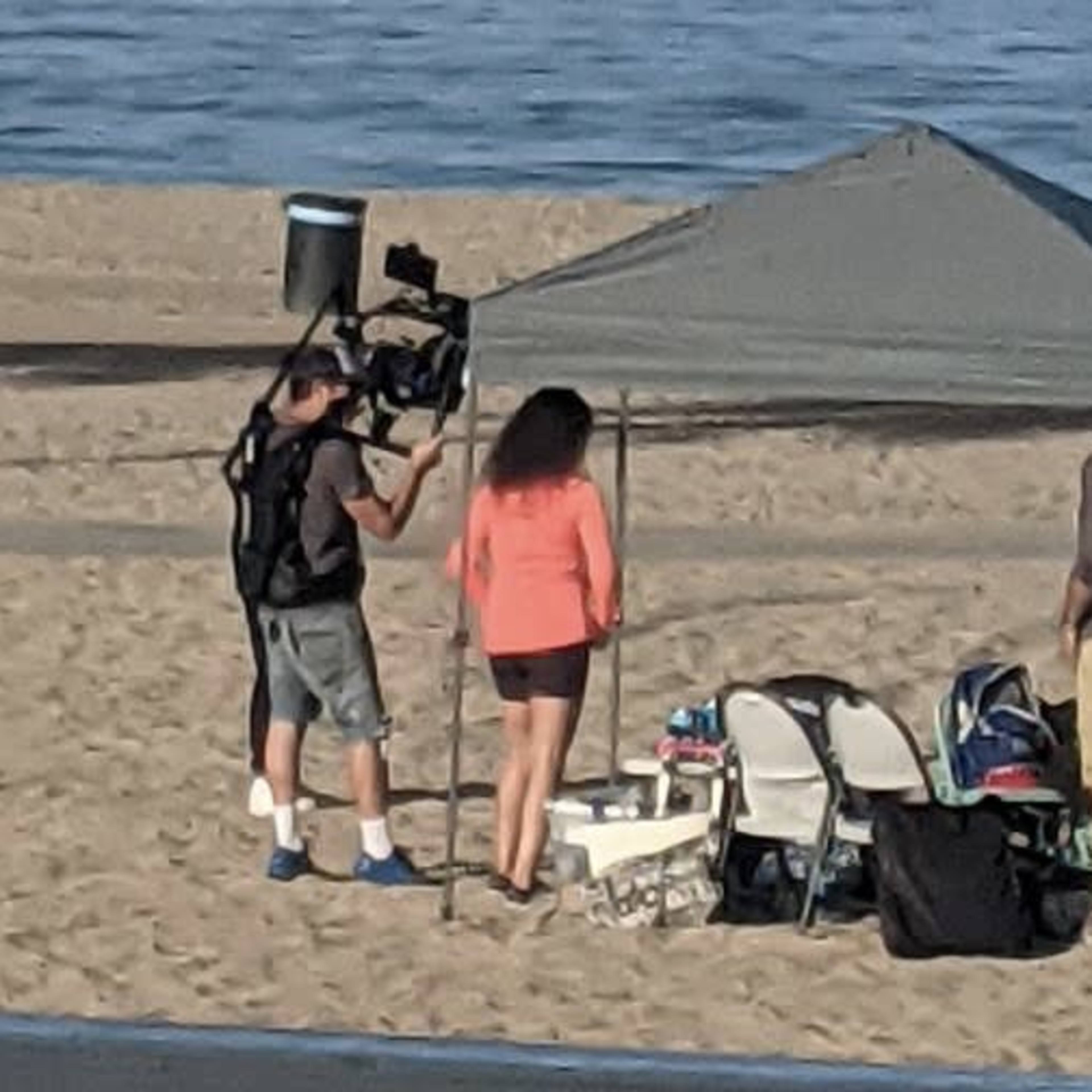 A group of people sets up equipment under a gazebo on a sandy beach.