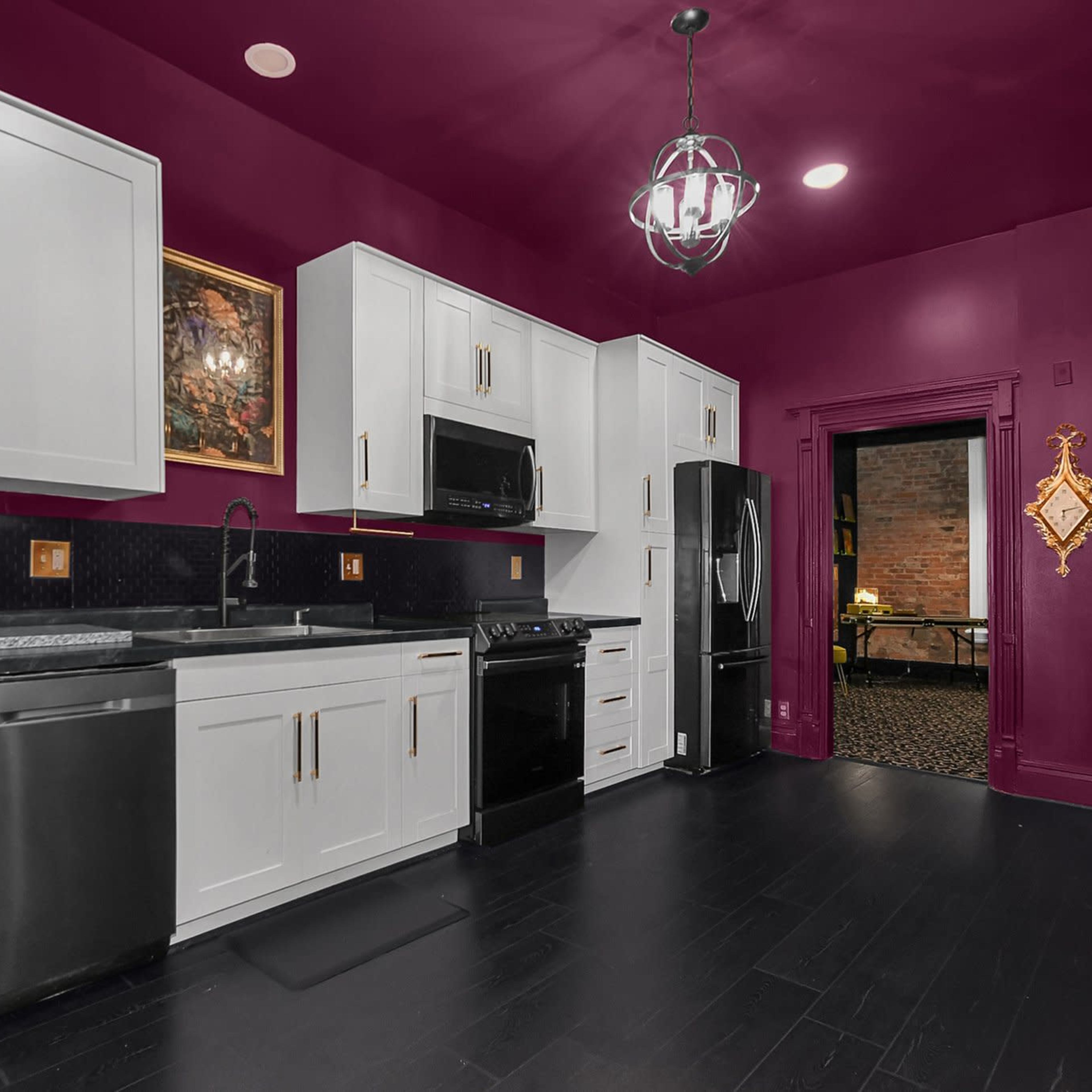 A kitchen with deep purple walls, white cabinetry, black appliances, and a dark floor.