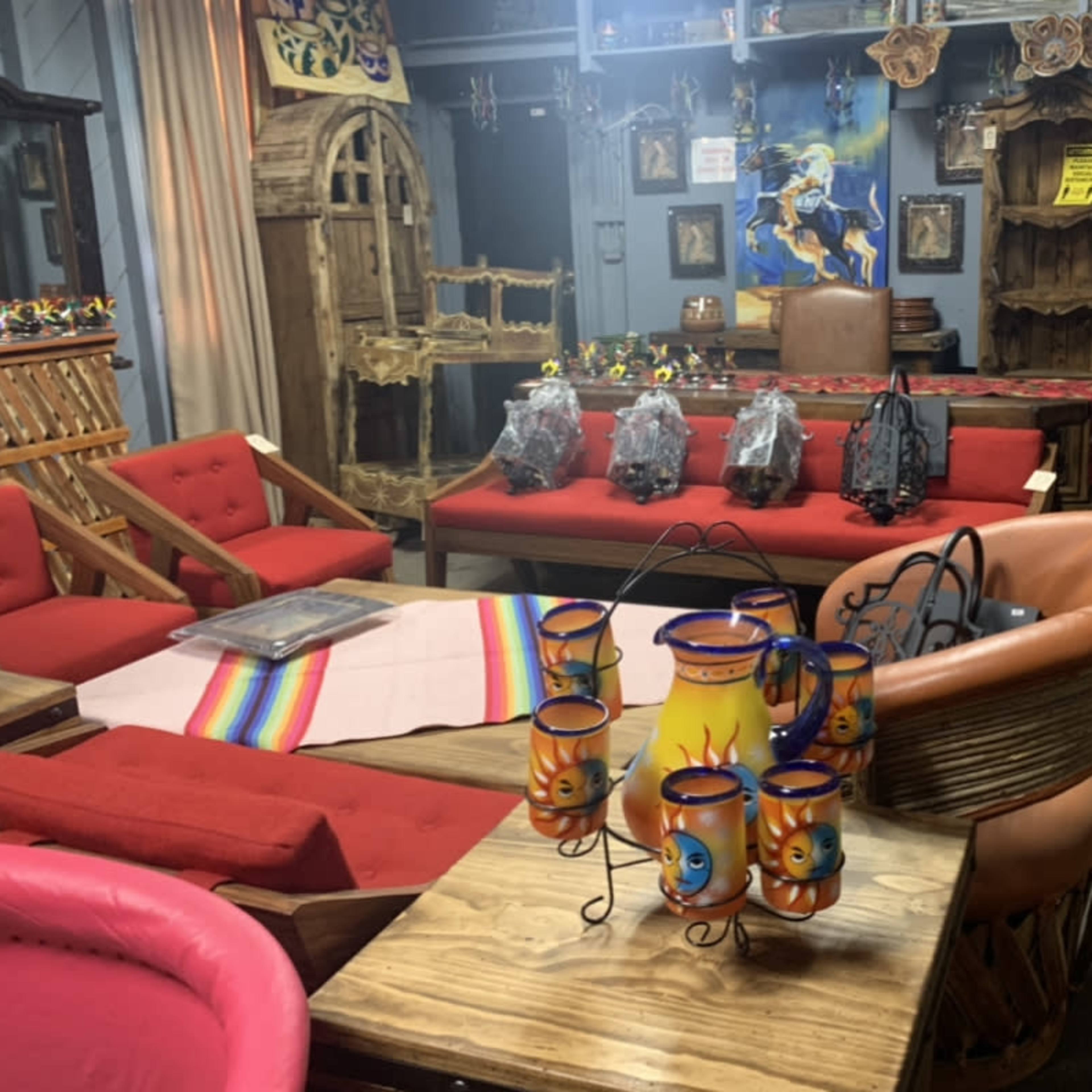 A colorful interior space featuring various wooden furniture pieces, decorative items, and woven textiles, with a focus on a table displaying a set of ceramic candle holders.