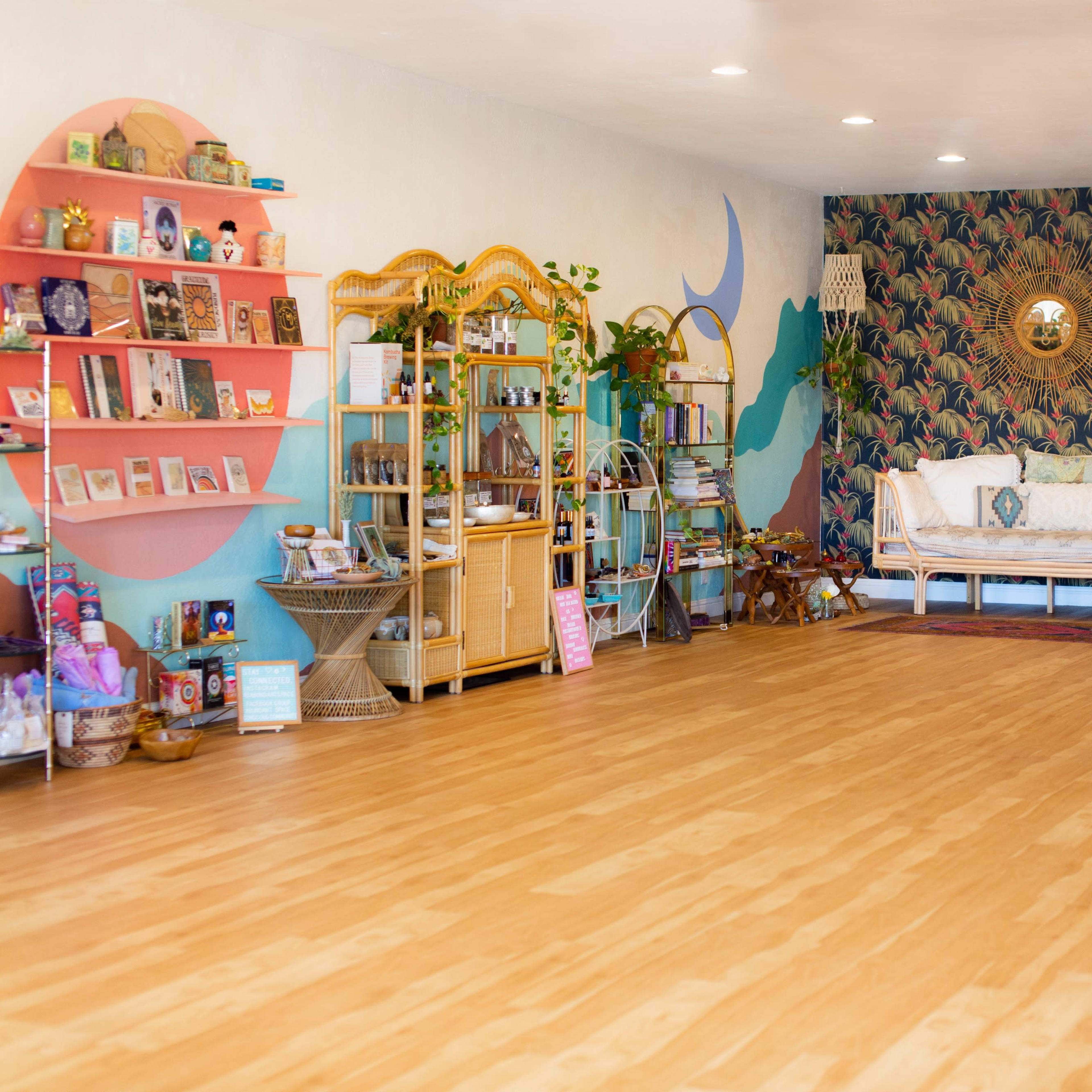 A spacious interior with wooden flooring, featuring a cozy seating area, shelves filled with books and decor, and a patterned accent wall.