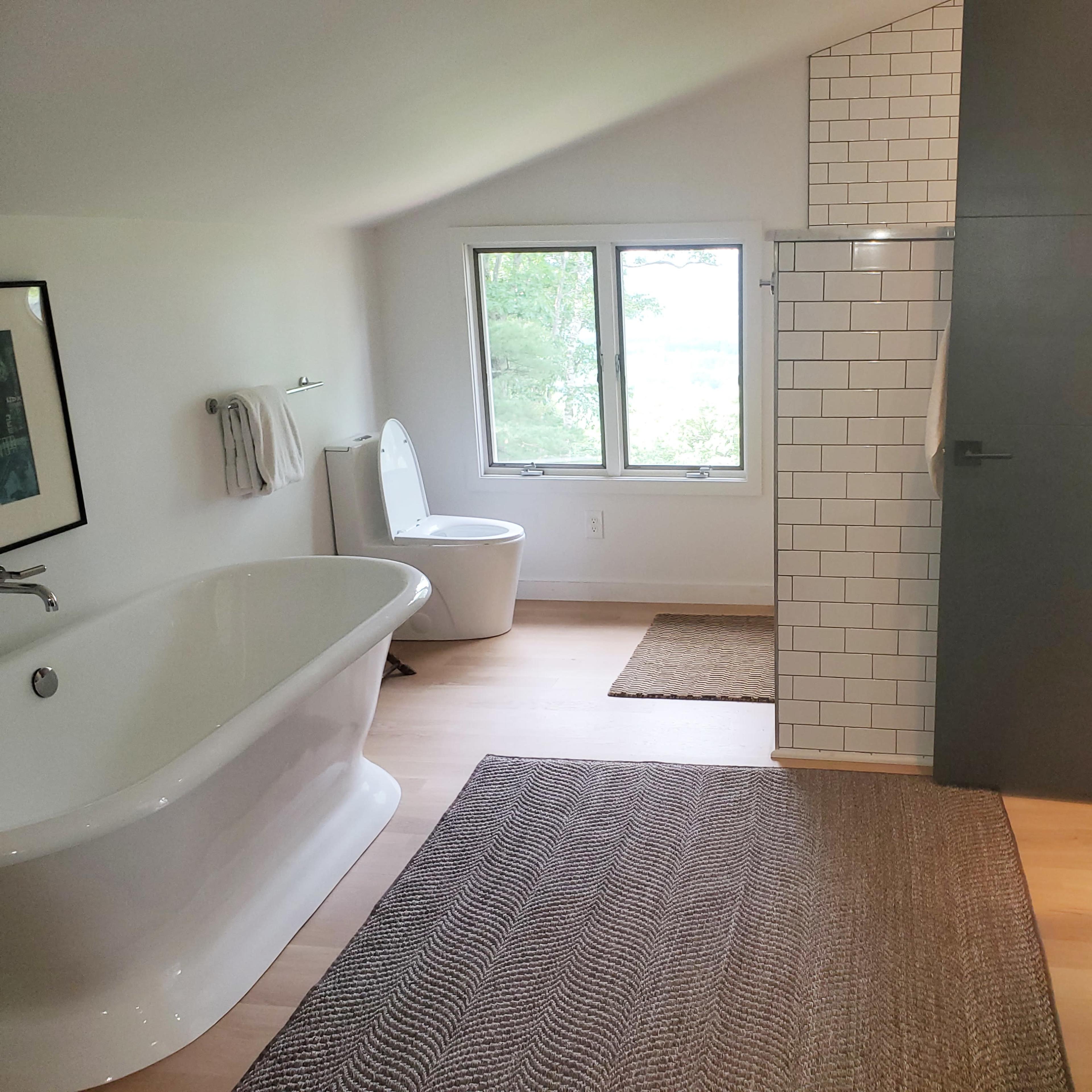 A modern bathroom featuring a freestanding bathtub, a walk-in shower with a glass partition, a toilet, and a double vanity with a marble countertop.