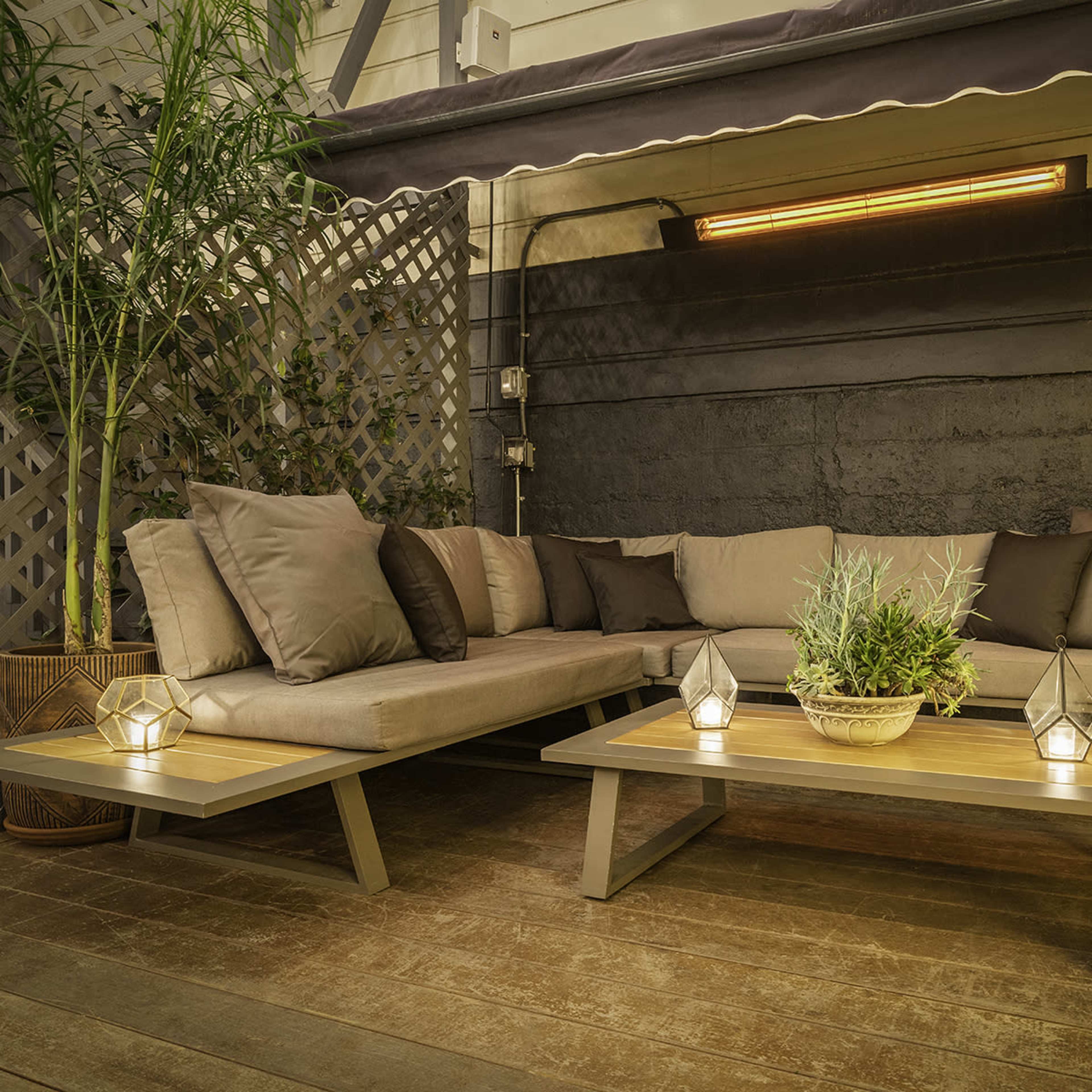 A modern outdoor seating area features a sectional sofa with brown cushions, a wooden coffee table, and decorative lanterns on a wooden deck.