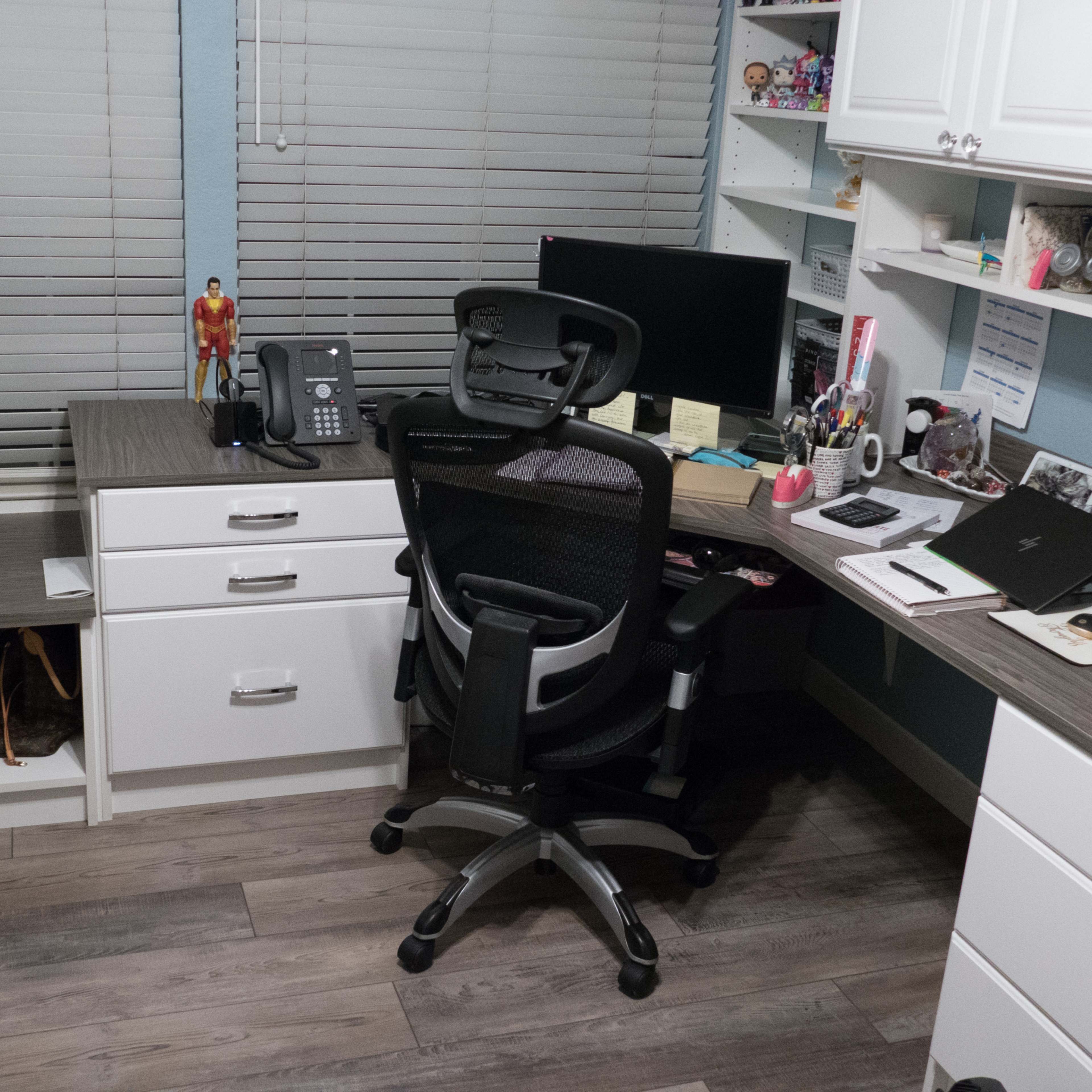 A home office with a desk, an ergonomic chair, a computer monitor, and storage cabinets, featuring organized supplies and personal items.