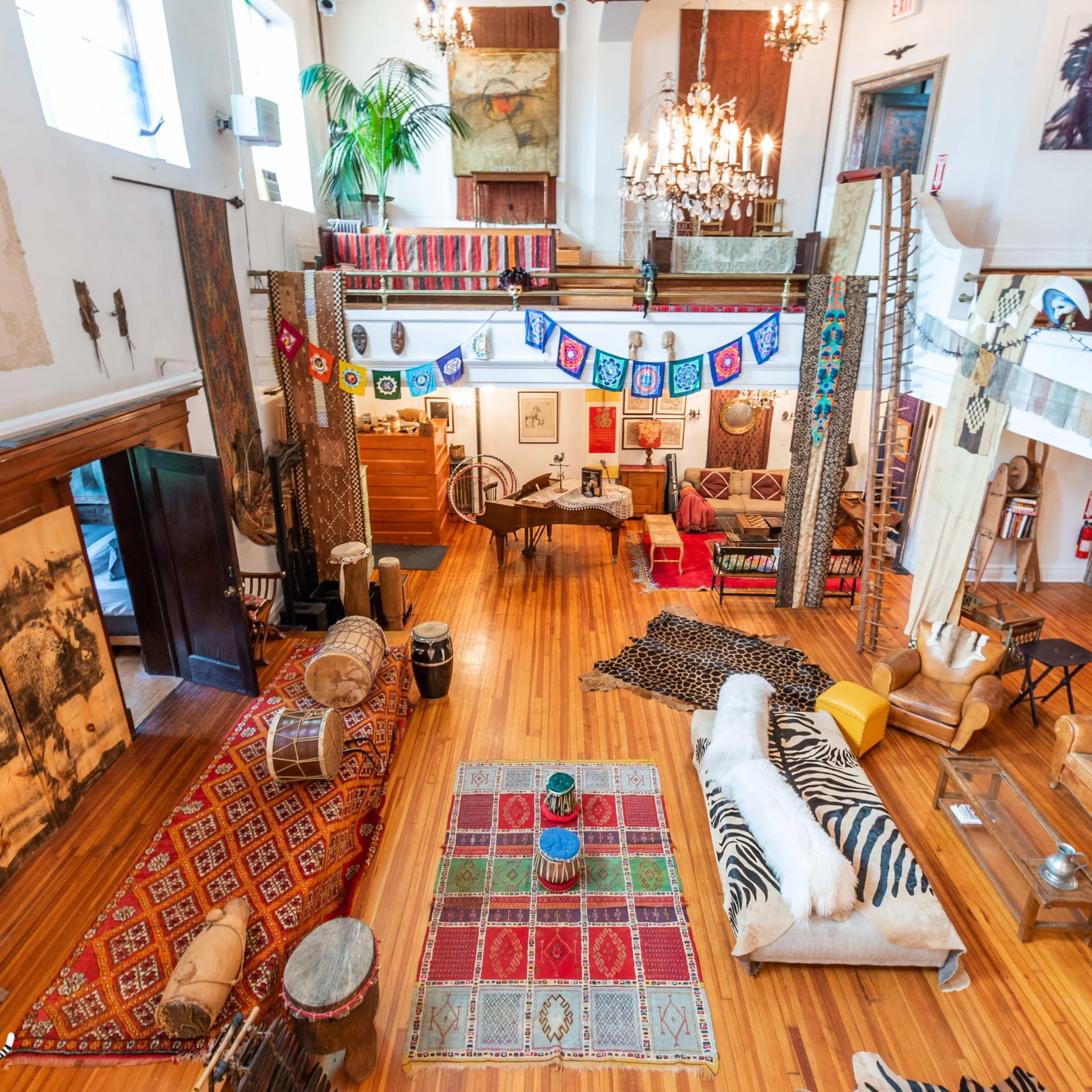 A spacious, decorated living area with various seating arrangements, colorful textiles, and artistic decor elements.