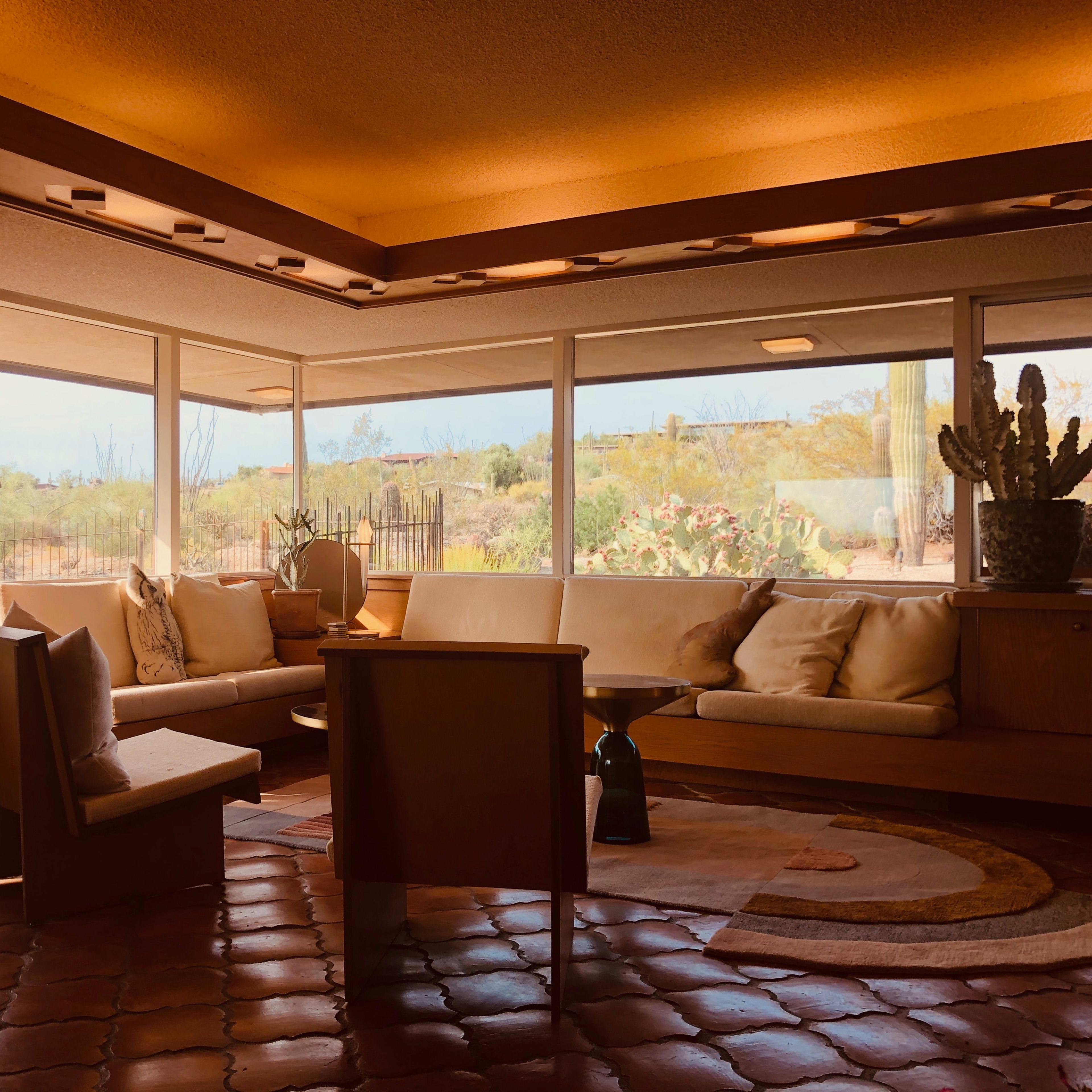 A spacious, sunlit living area with large windows that provide a view of the desert landscape outside.