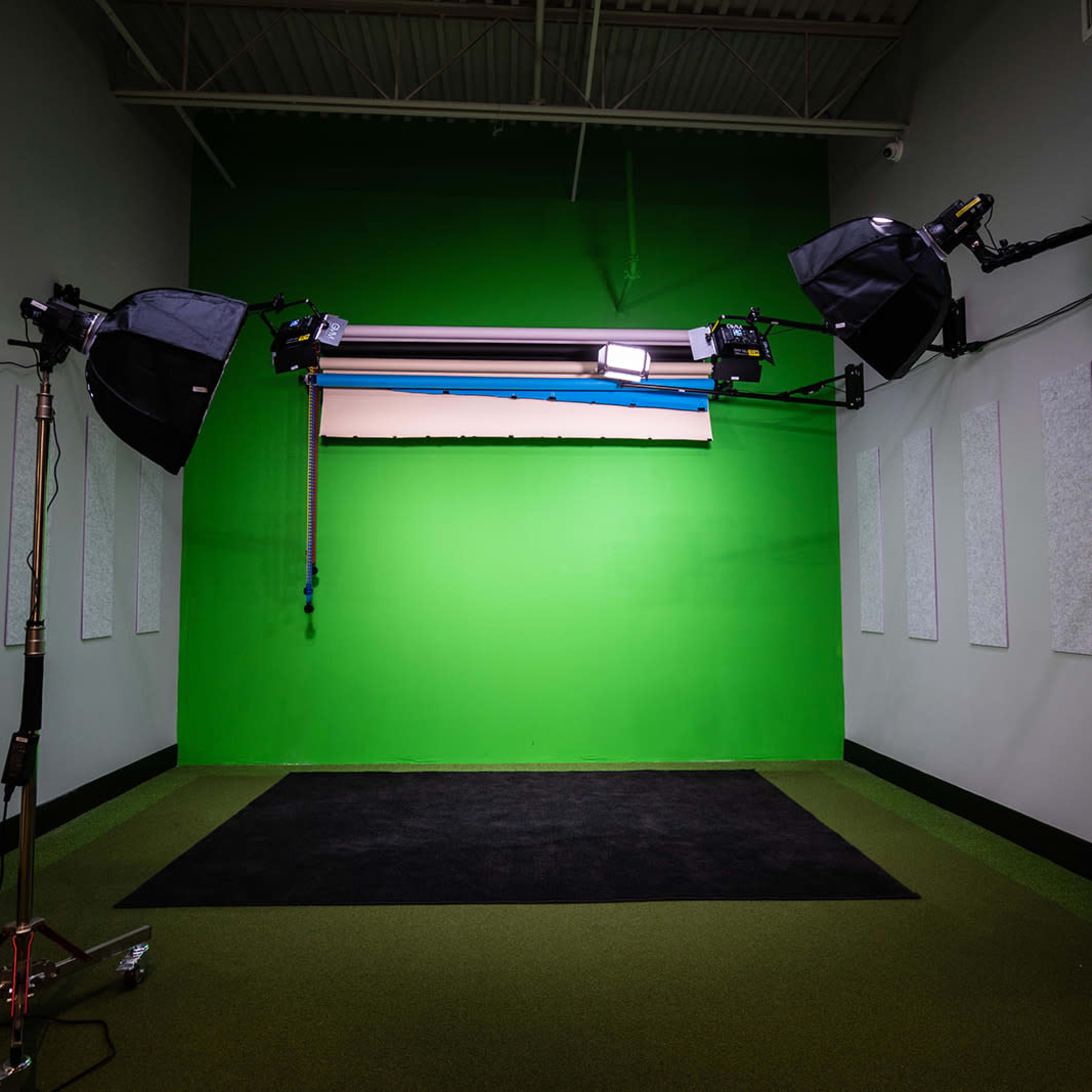 A green screen studio equipped with lighting fixtures and soundproof panels on the walls.