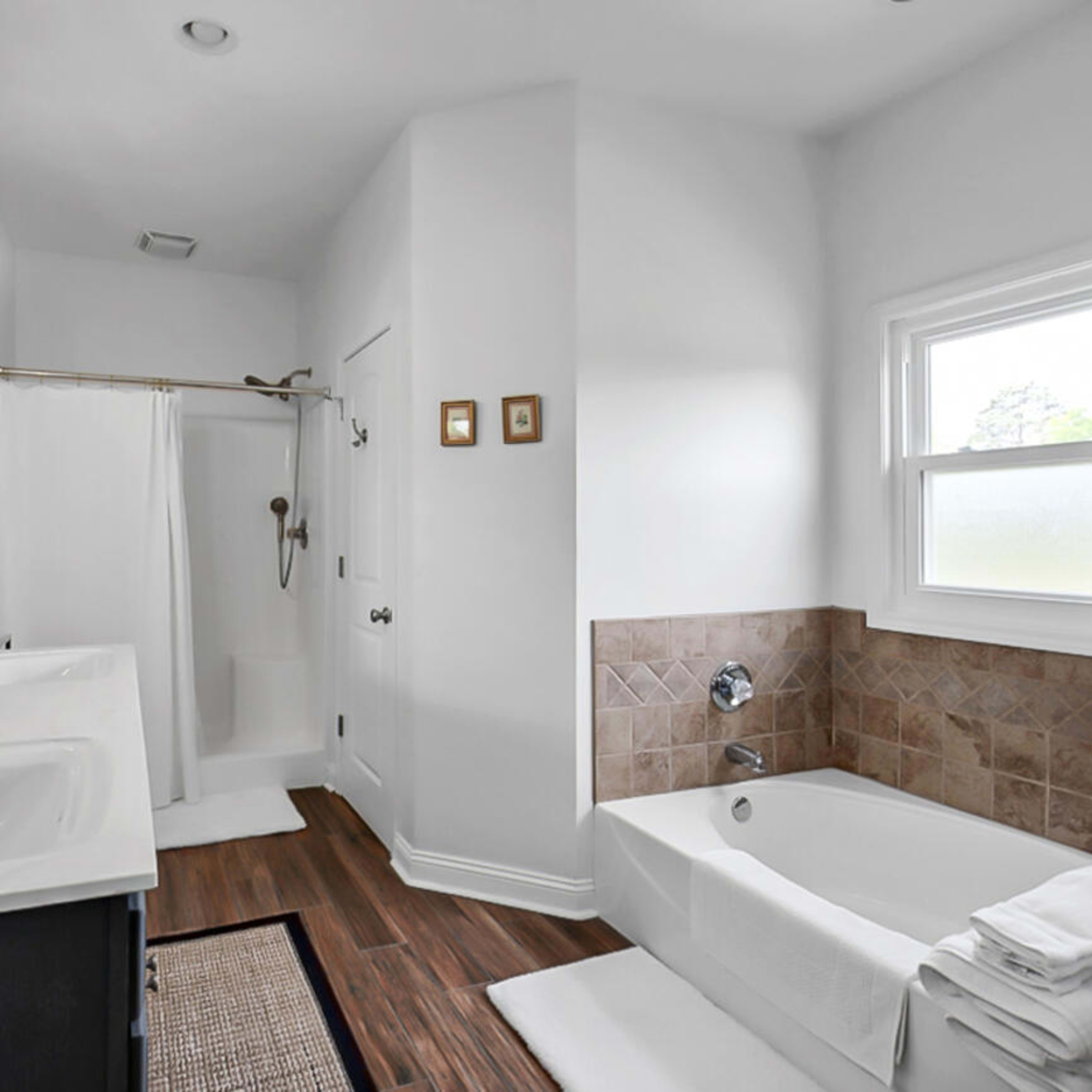 The bathroom features a double vanity with two sinks, a walk-in shower, a bathtub, and neutral-colored tile accents.