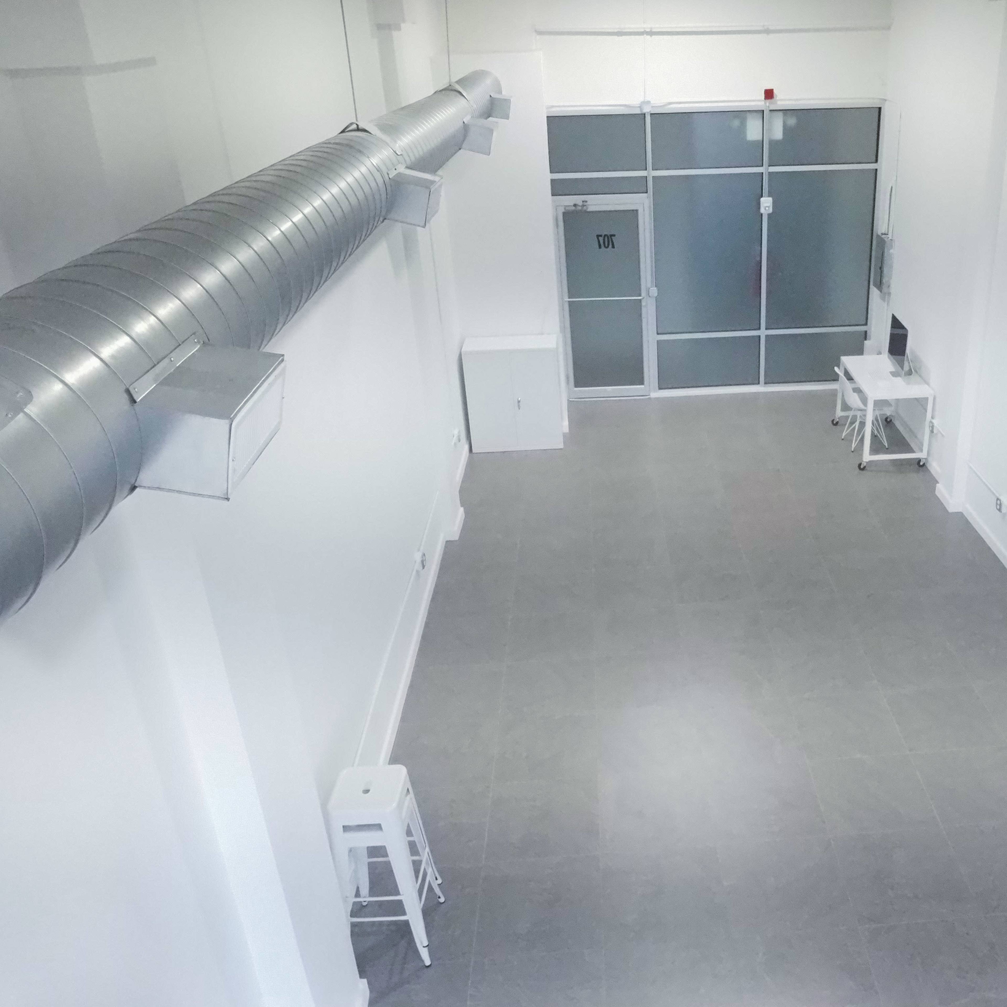 A spacious, empty room with gray tiled flooring, white walls, and a large glass door at one end.