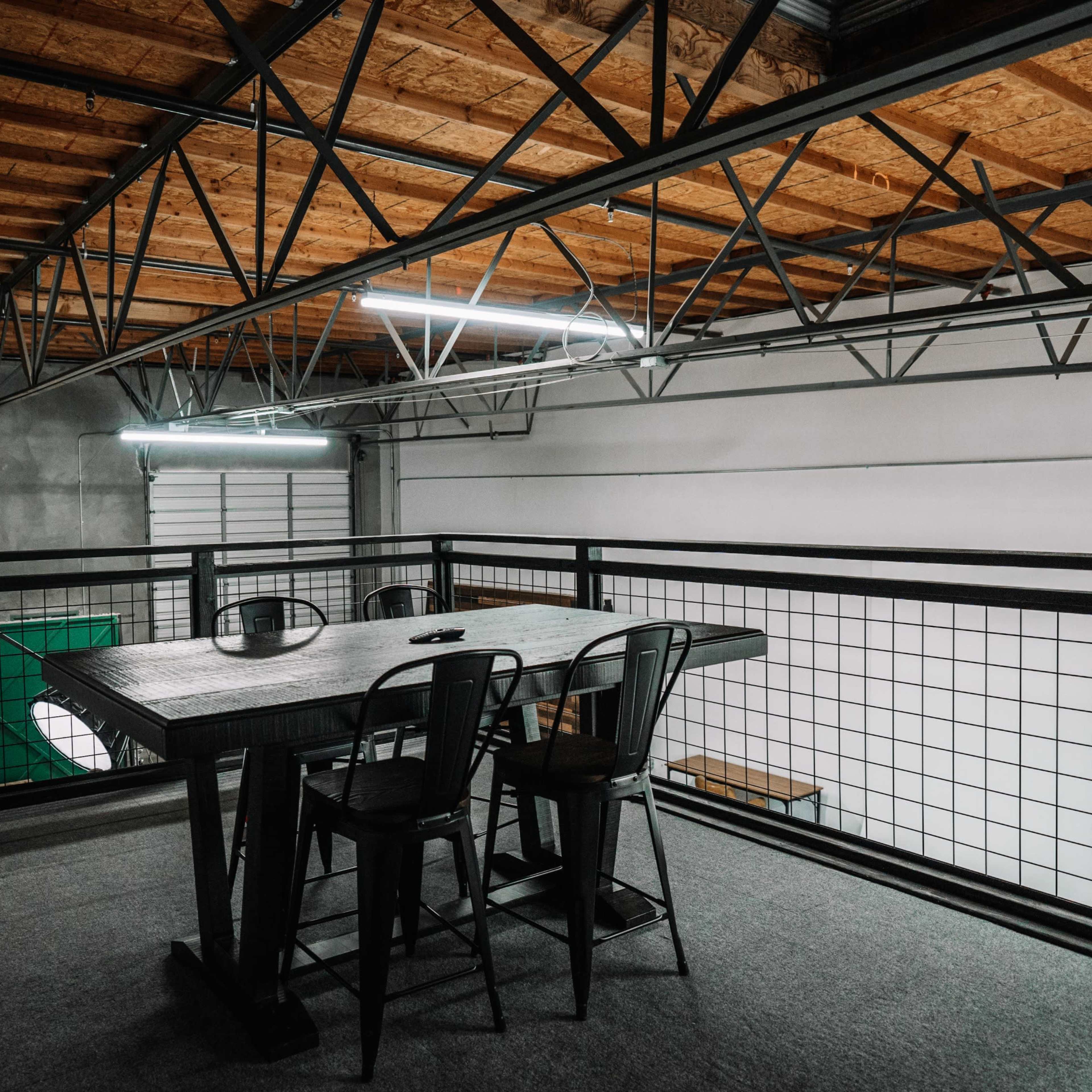 A spacious loft area features a table with chairs, overlooking a large open room fitted with a green surface.