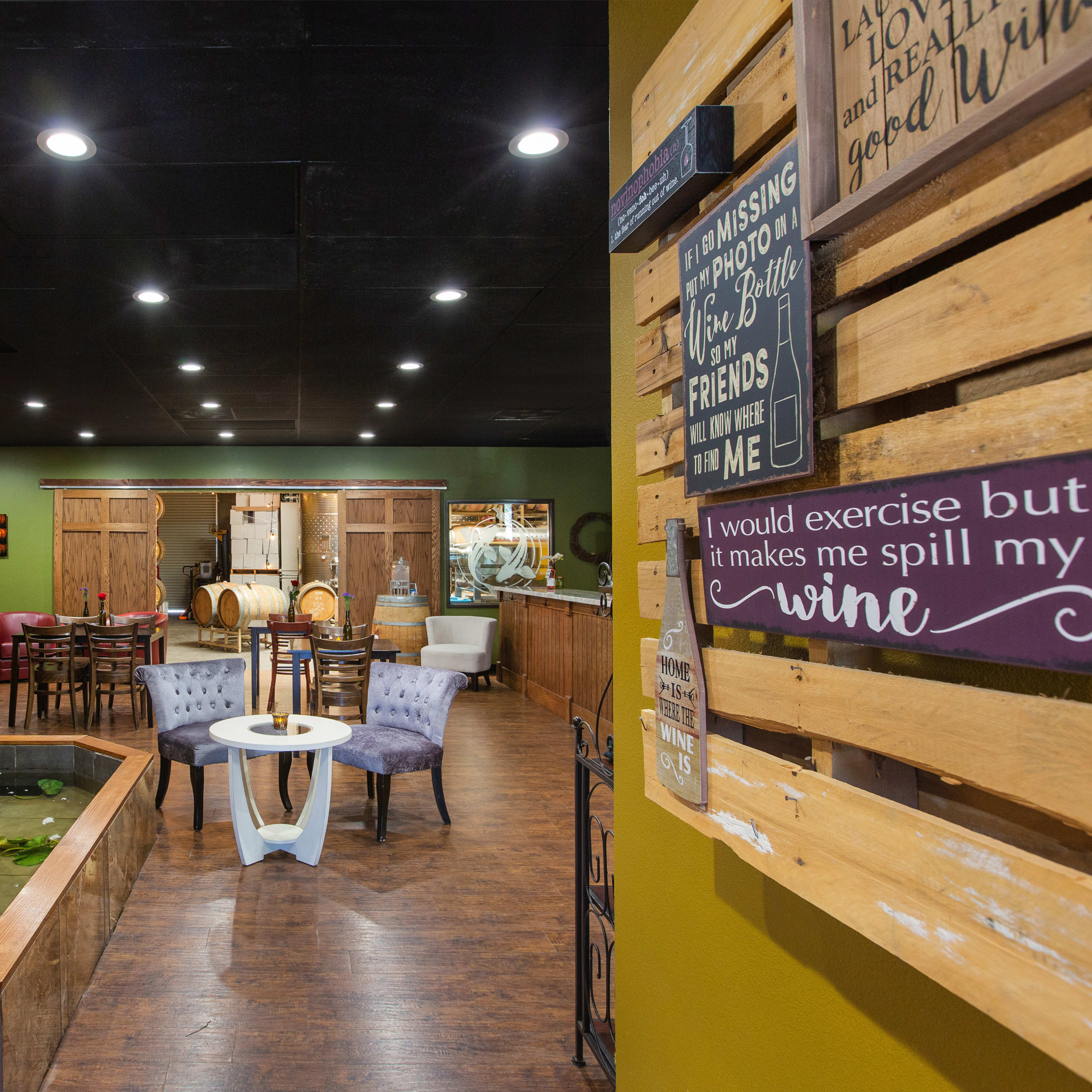 A cozy interior of a wine-themed establishment featuring stone walls, a small water feature, and seating areas with wooden decor.