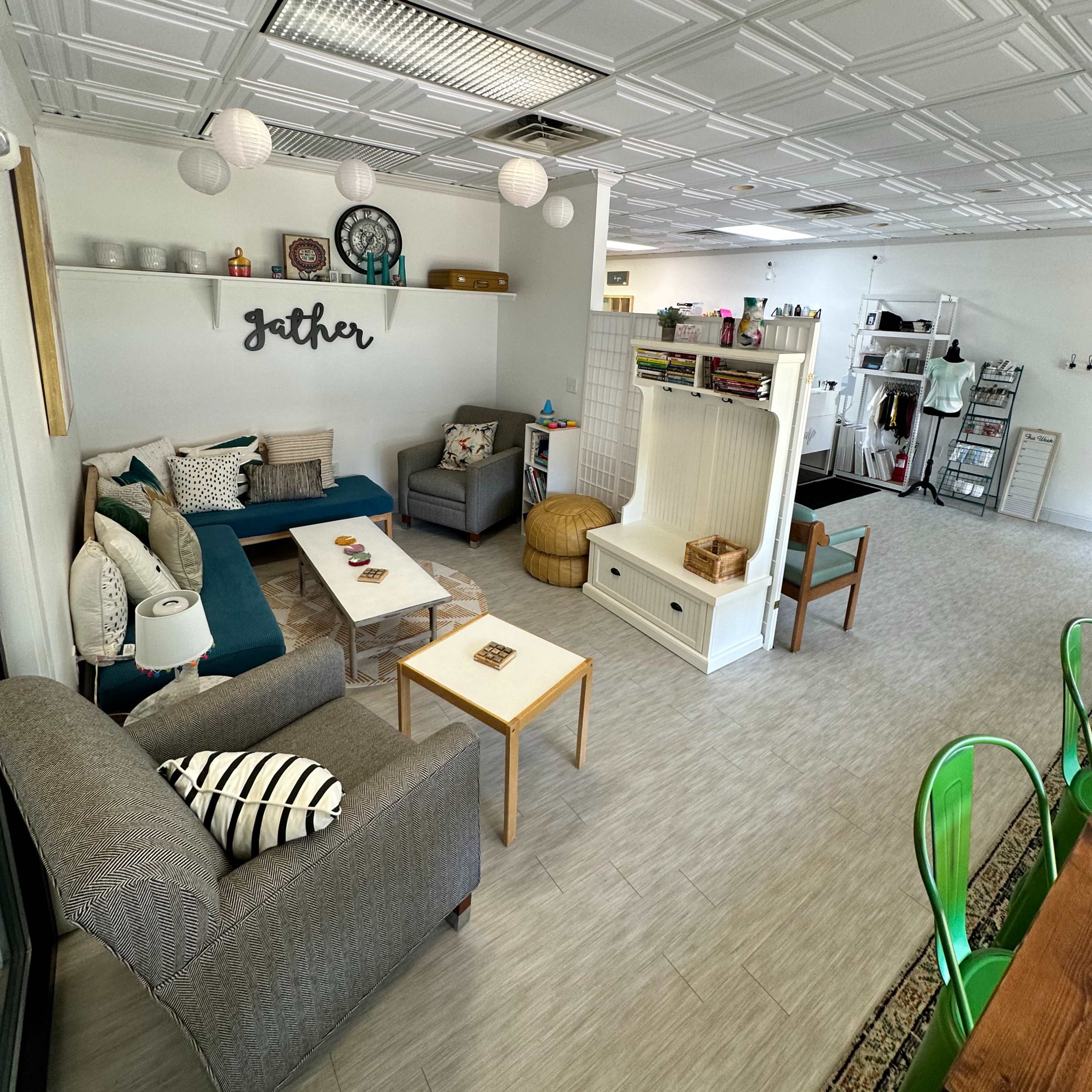 A modern communal space featuring comfortable seating, a coffee table, and decorative elements, with a dining area visible in the background.