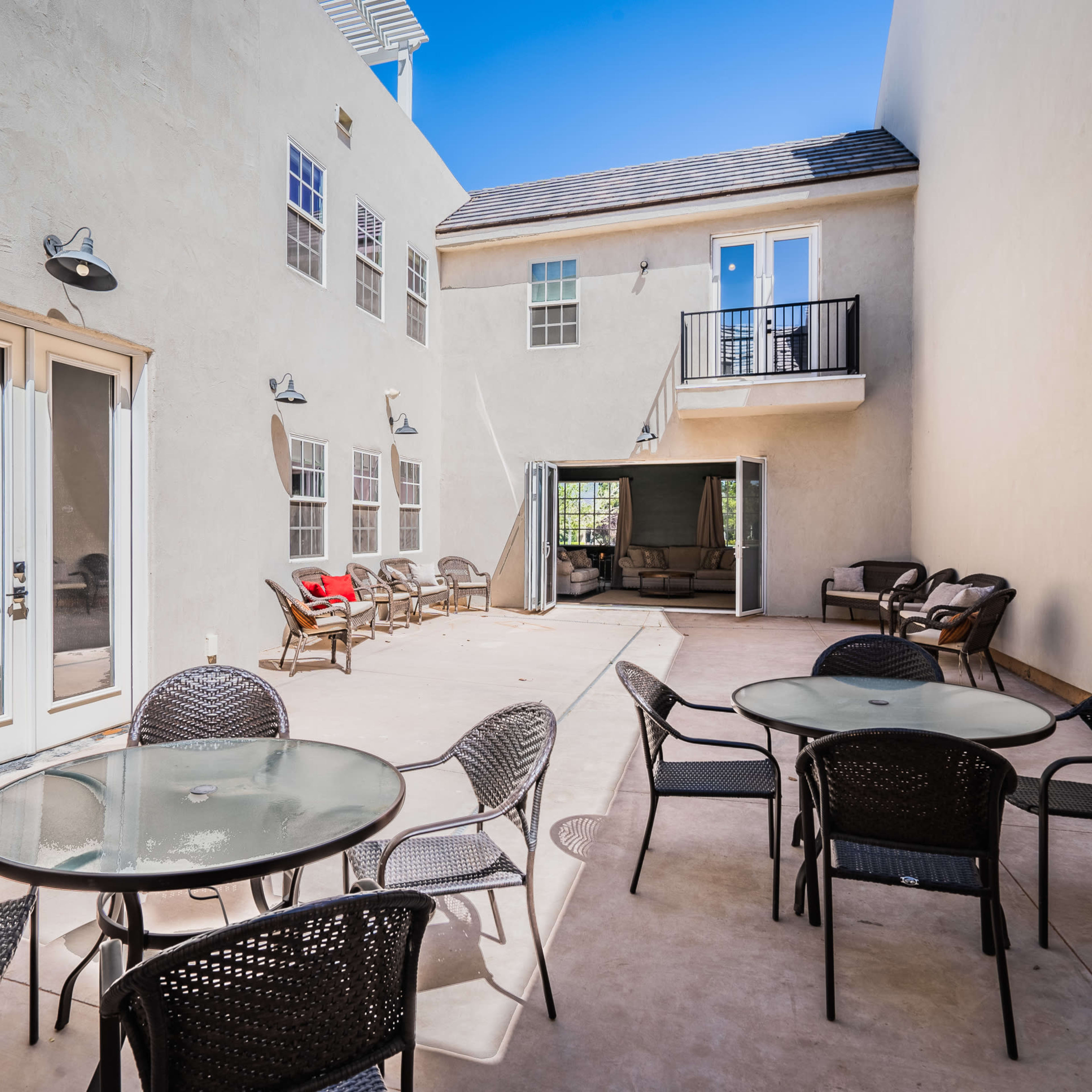 A courtyard with several tables and chairs, flanked by buildings on two sides.