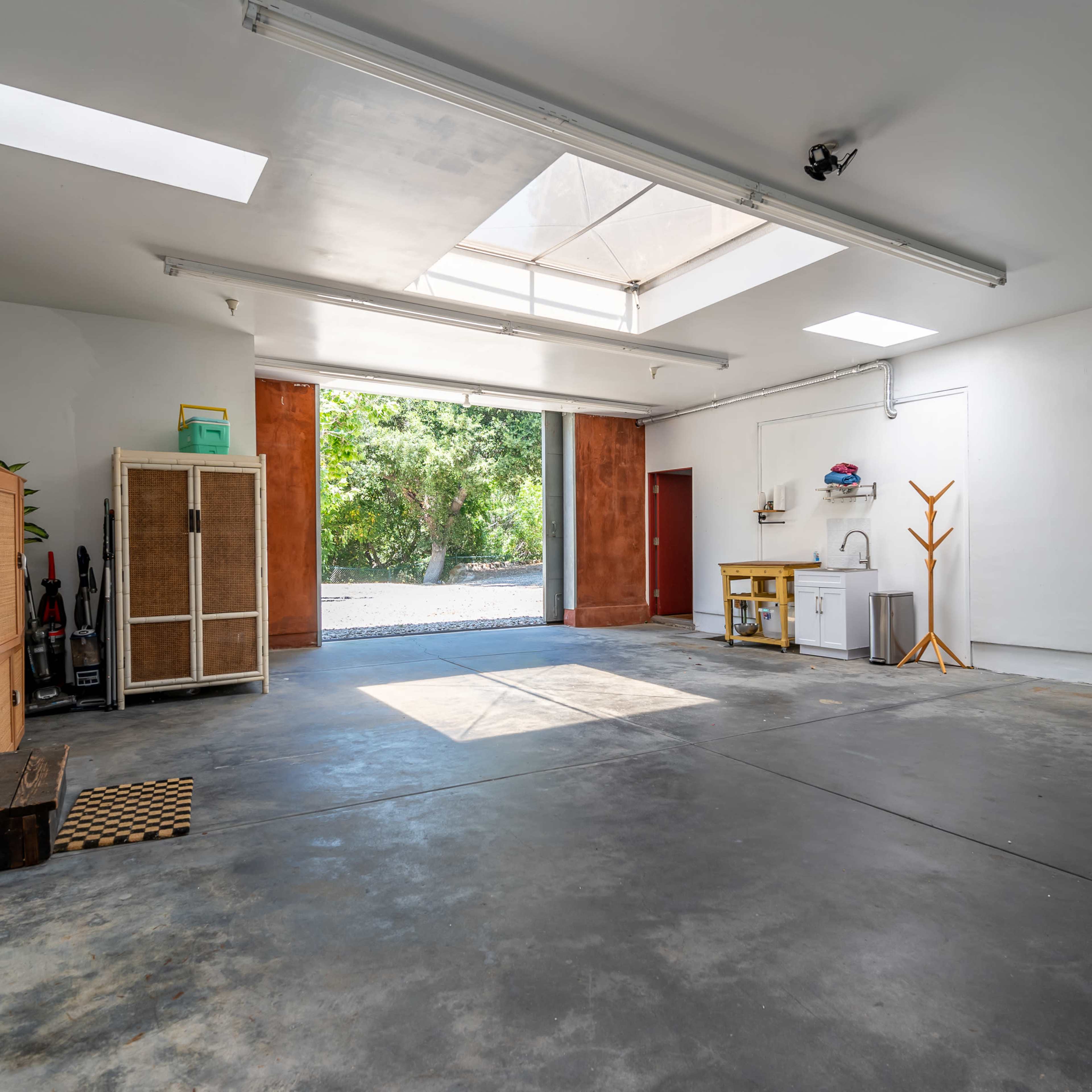 A spacious, well-lit garage with a concrete floor, large windows, and a few basic storage items along the walls.
