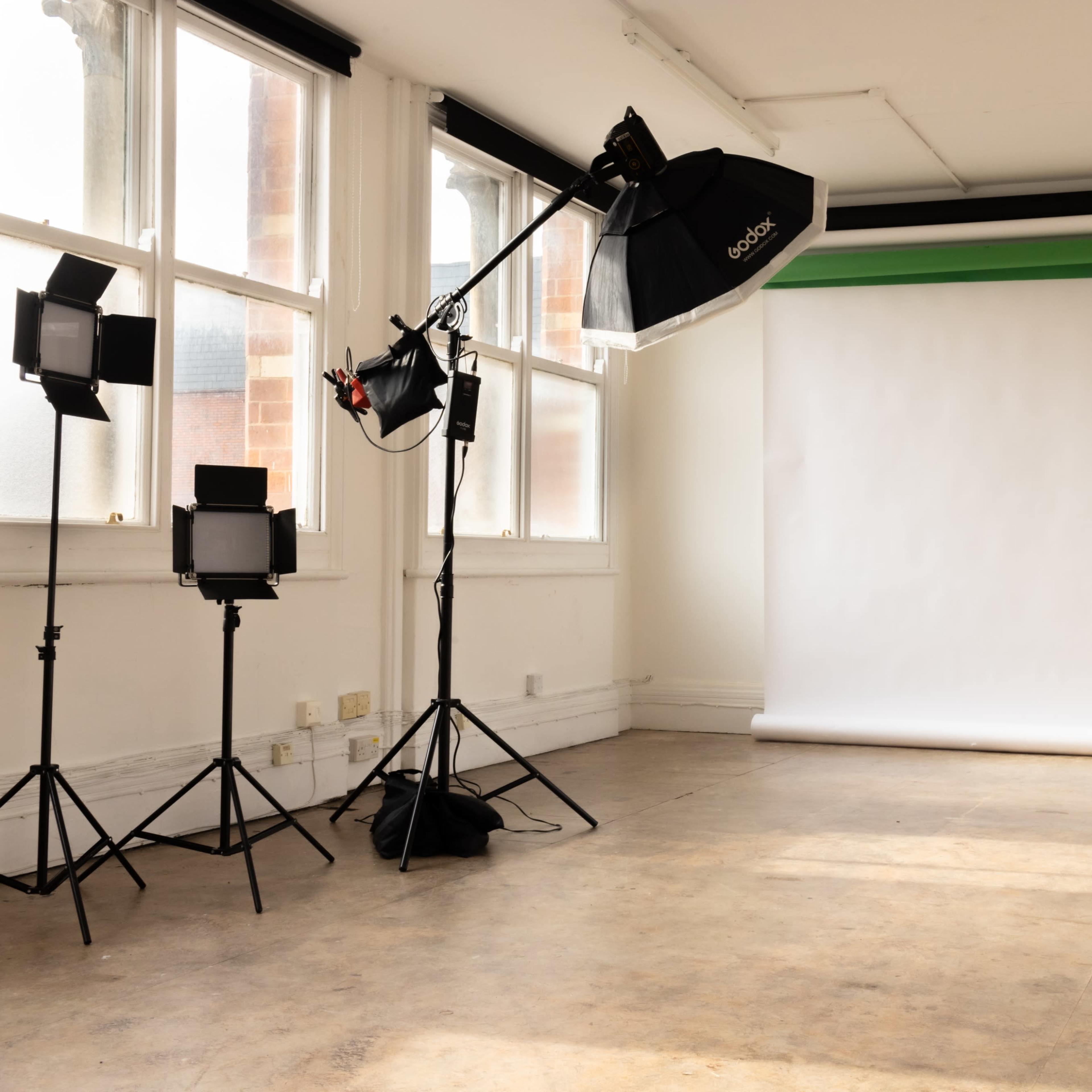 A photography studio equipped with multiple lights and a plain backdrop.