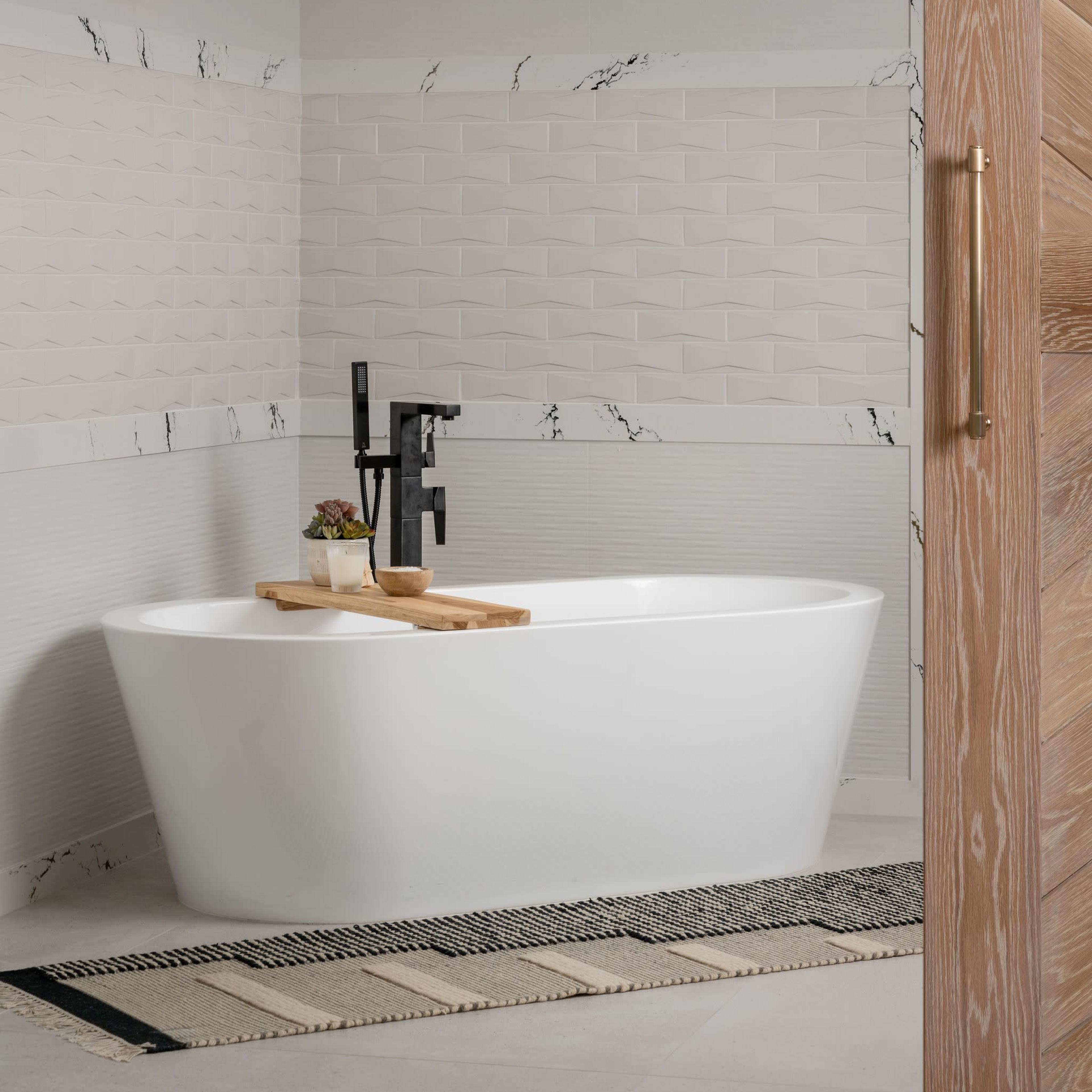 A modern bathroom featuring a freestanding white bathtub, a decorative chandelier, and stylish wall tiles with a black and white color scheme.