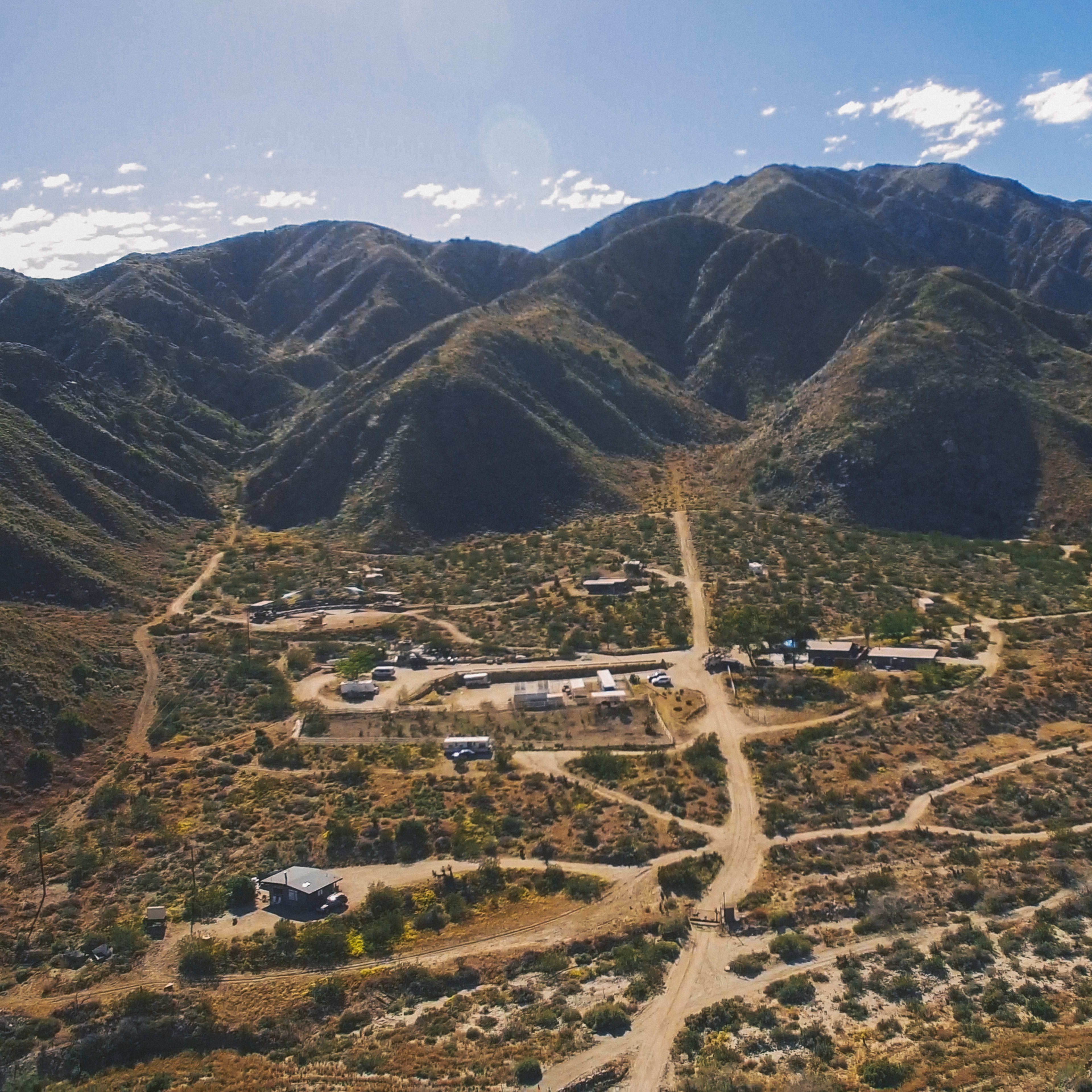 A mountainous landscape with a small settlement and dirt roads winding through arid terrain.