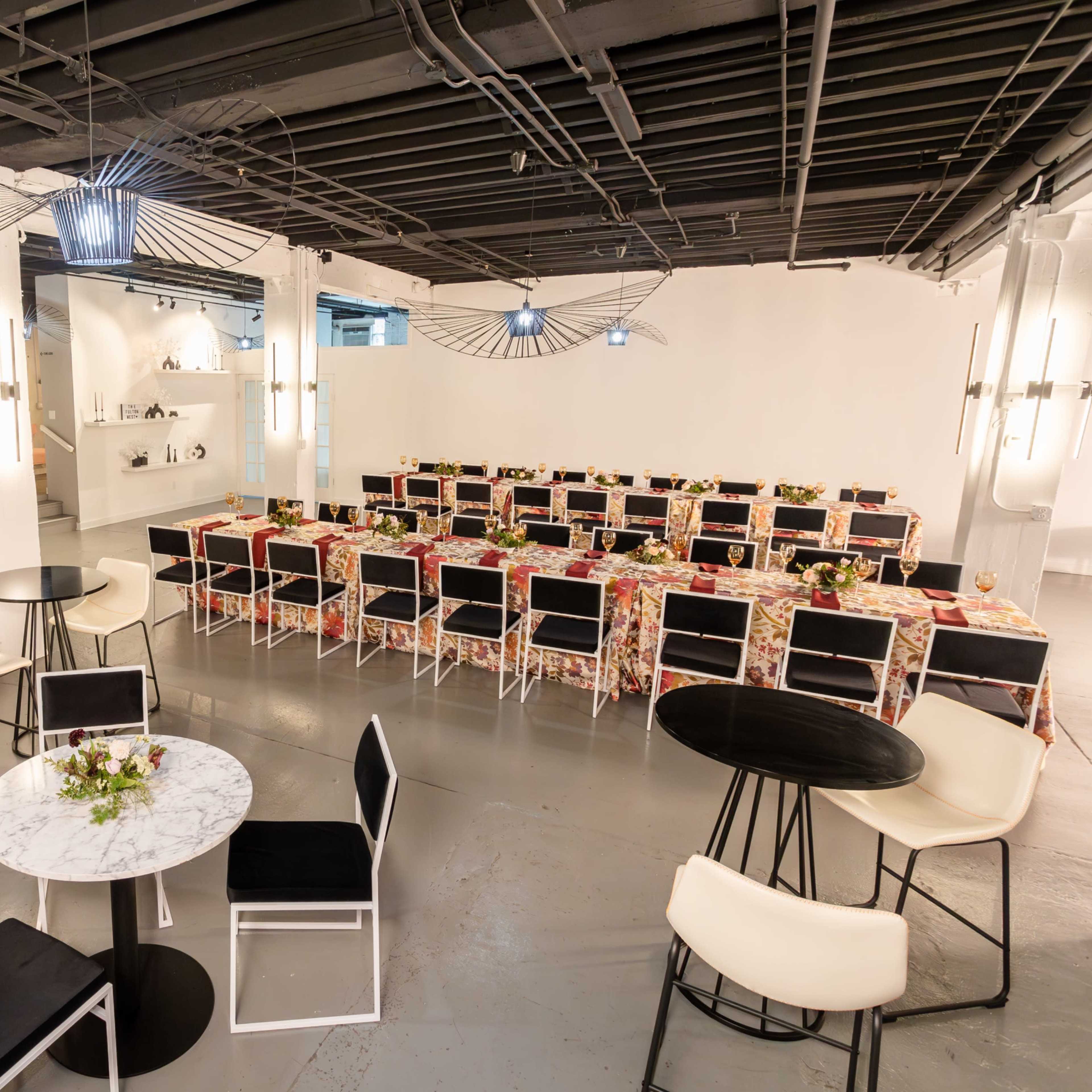 A spacious event venue arranged with tables and chairs, featuring a central dining area adorned with floral table settings.