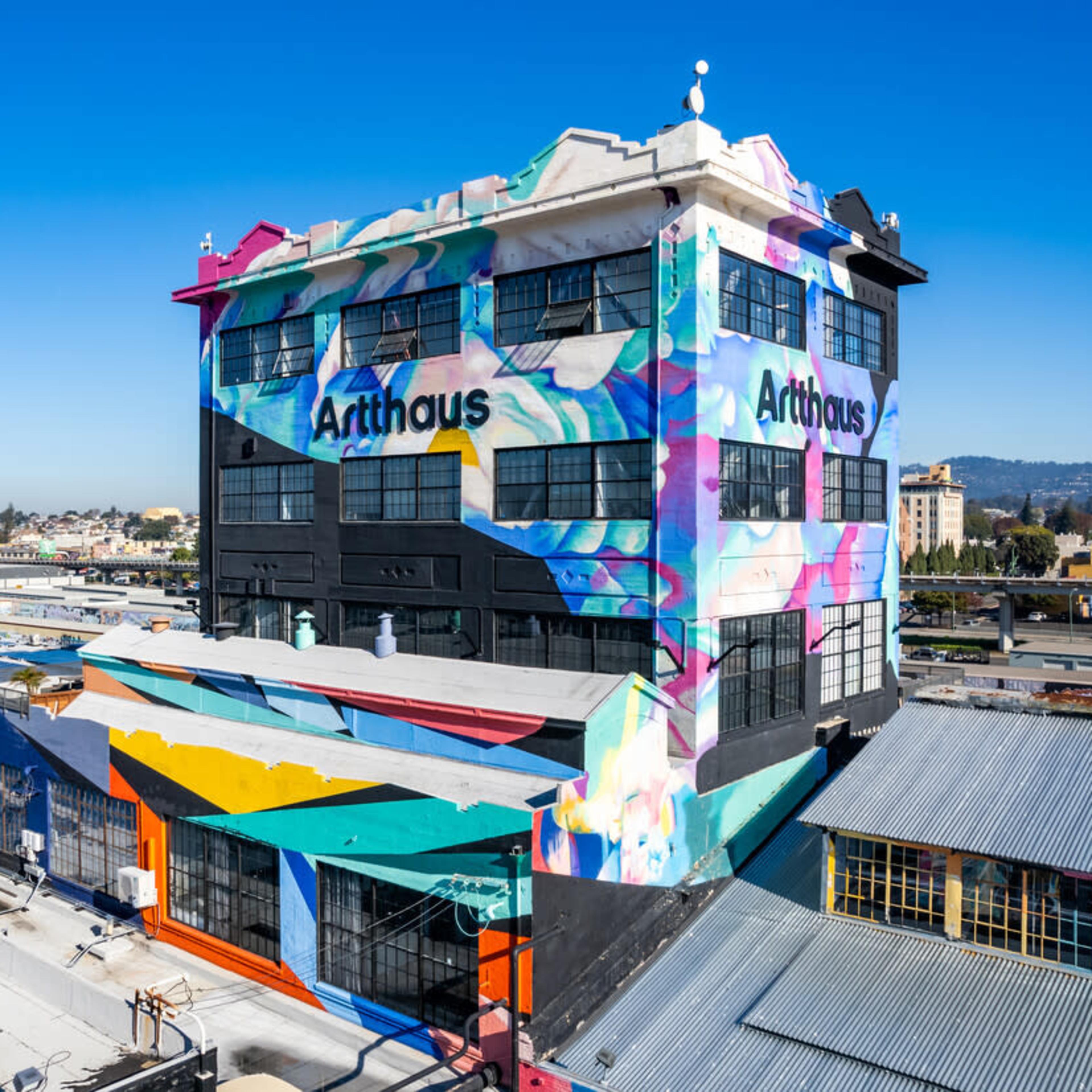 A colorful, graffiti-covered building named "Arthaus" situated in an urban area with clear blue skies in the background.