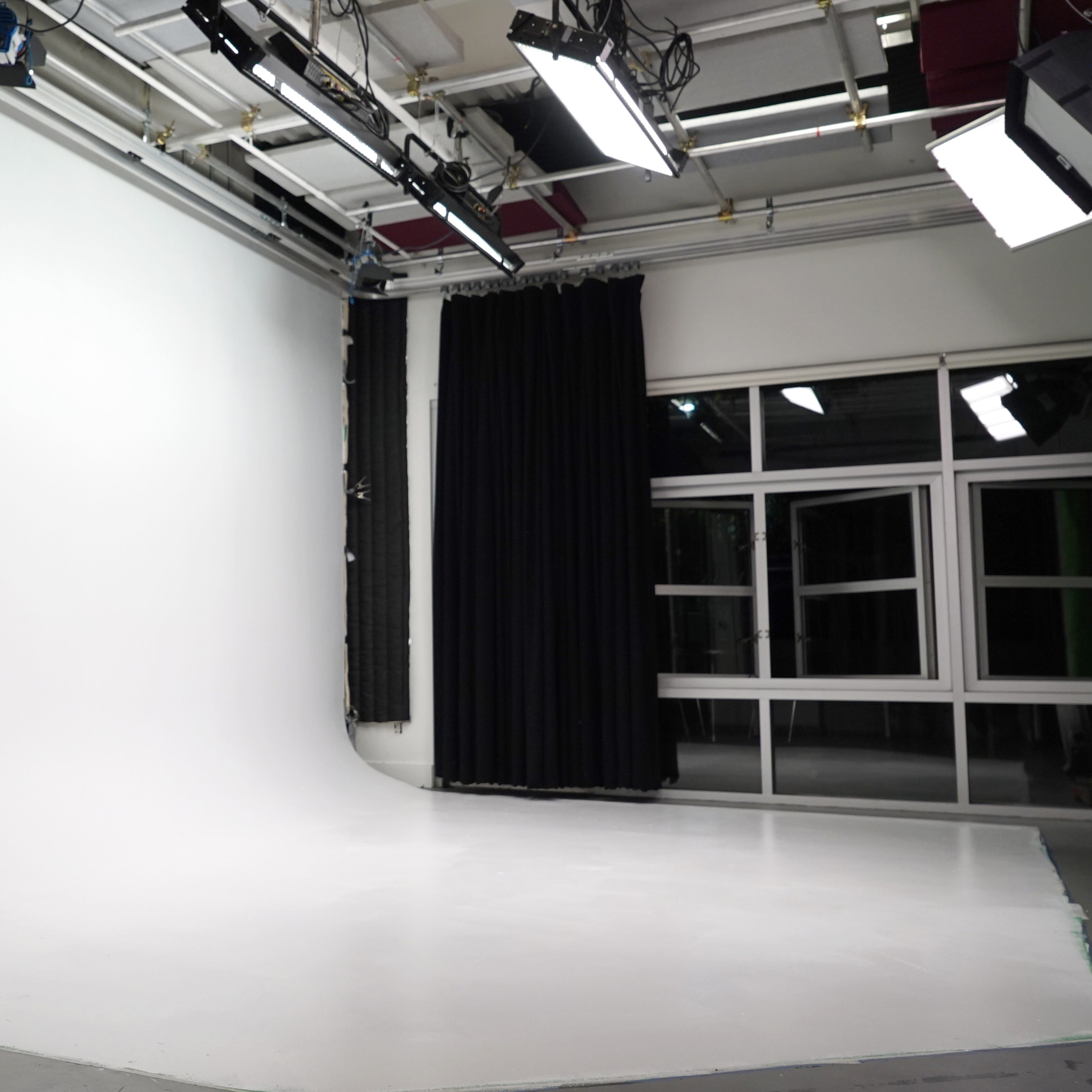 A well-lit photography studio with a large white backdrop and a dark curtain.