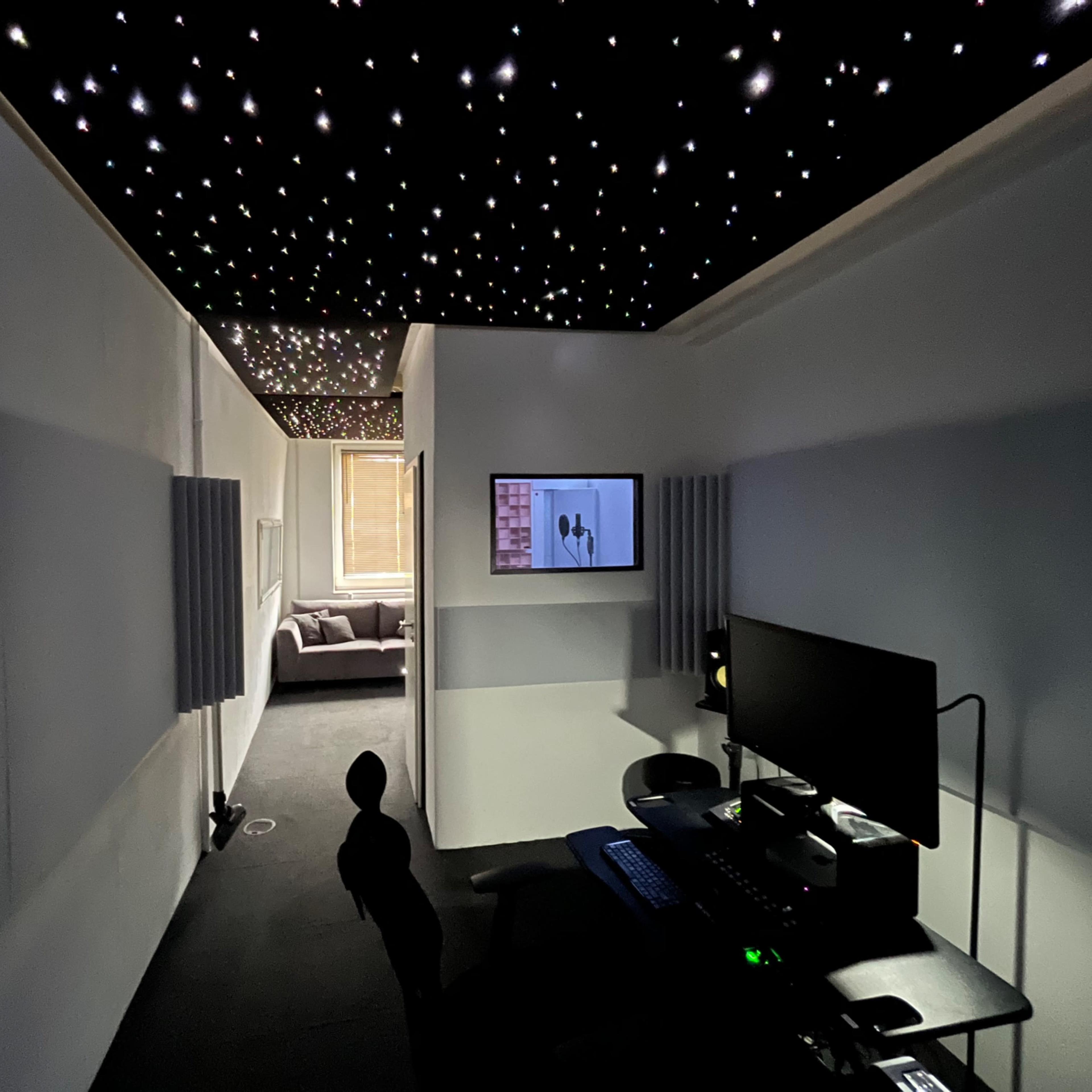 A dimly lit corridor leads to a comfortable living area, with a ceiling resembling a starry sky and a workstation on the side.