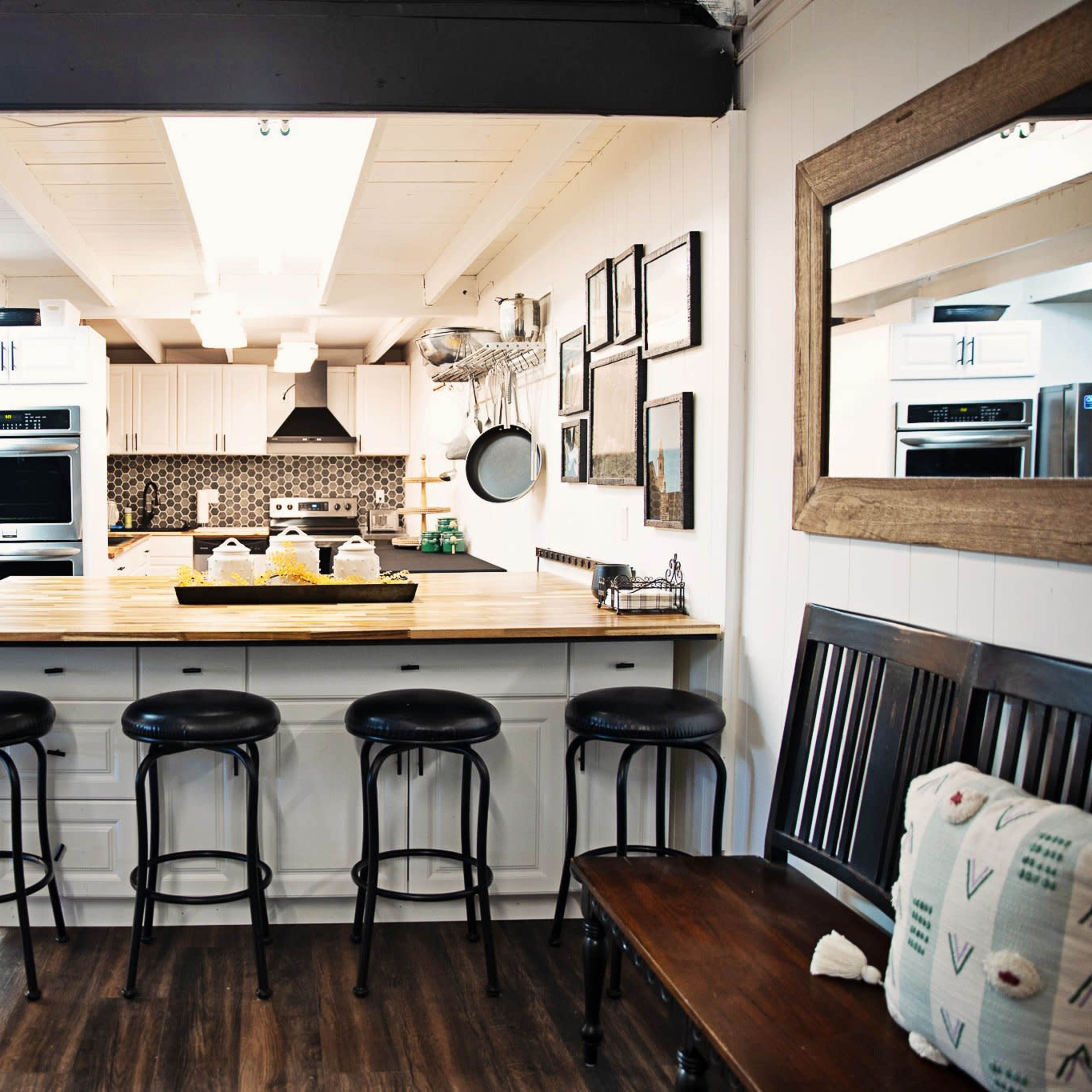 A modern kitchen features a central island with seating, stainless steel appliances, and a wooden countertop, all illuminated by overhead lights.