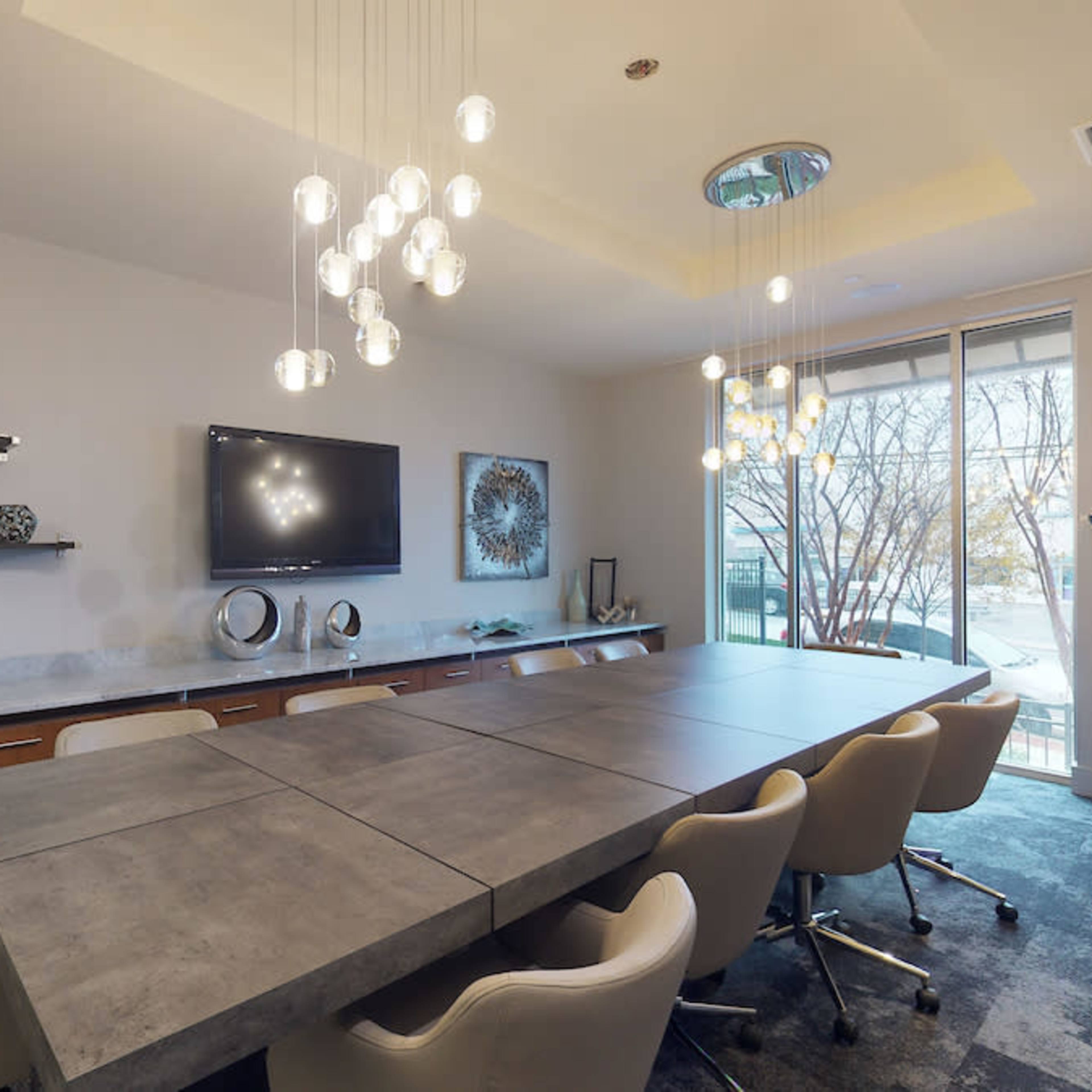 A modern conference room with a long concrete table, white chairs, and decorative wall shelves featuring various objects and art.