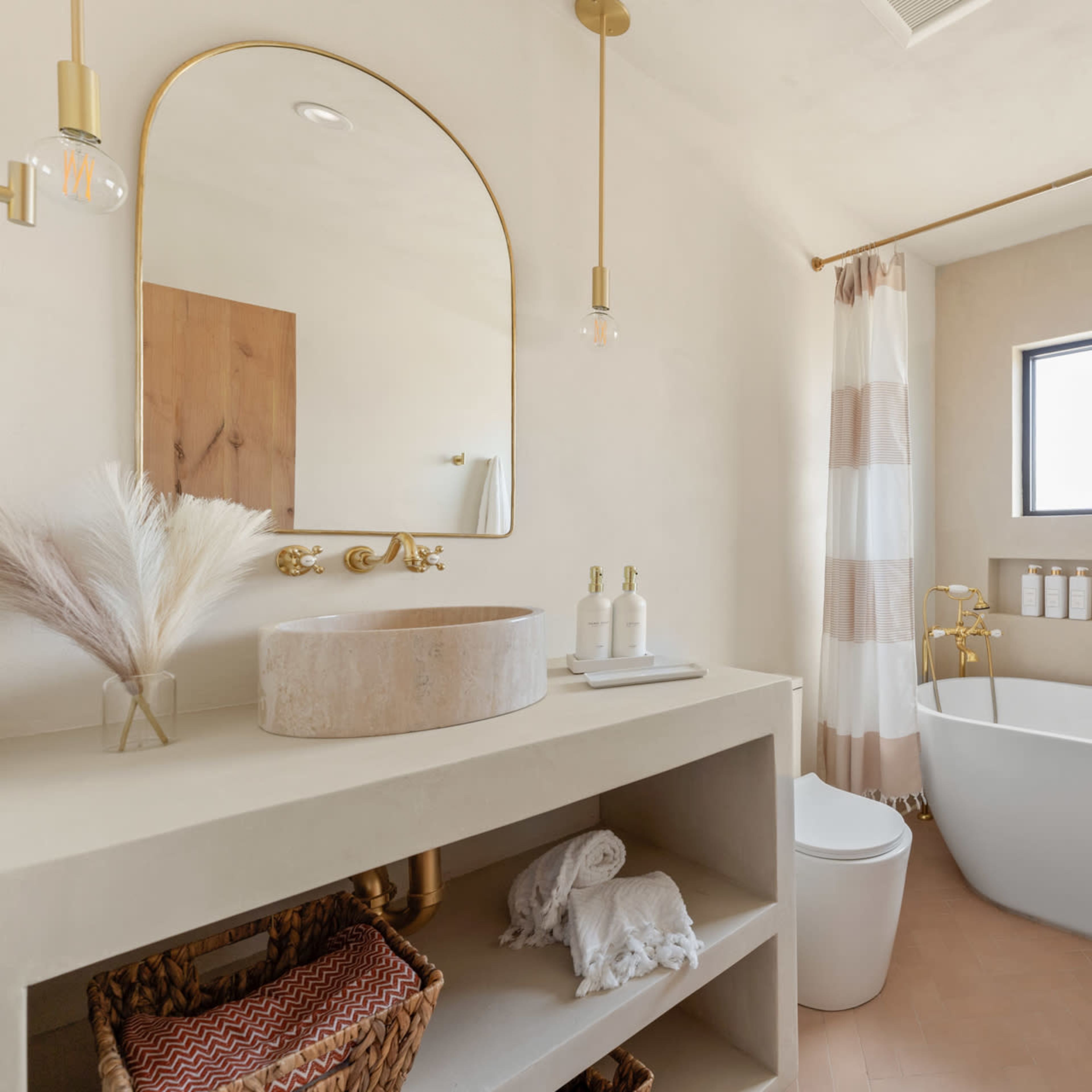 A modern bathroom features a freestanding bathtub, a large mirror, a minimalist vanity, and natural light coming through a rectangular window.