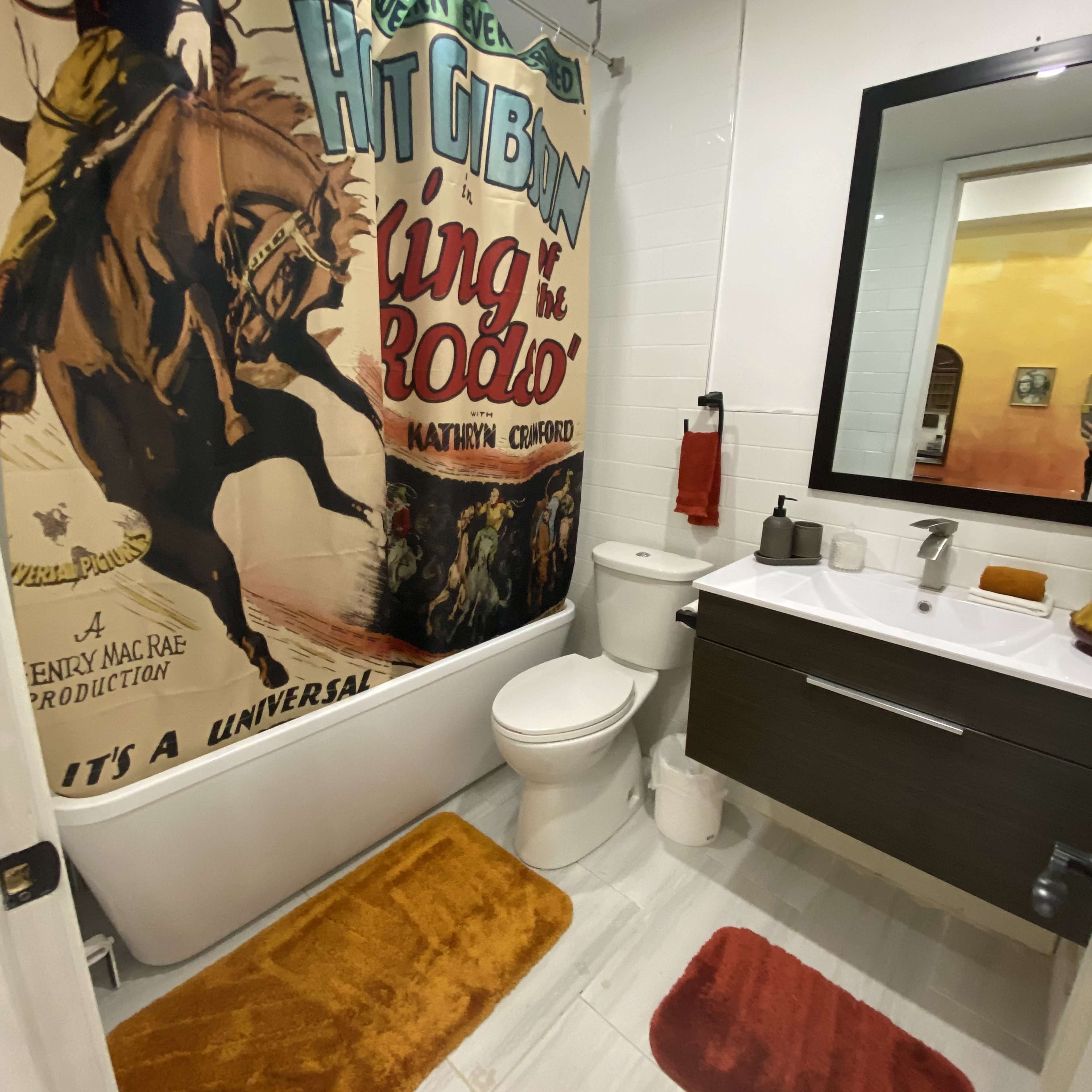 A bathroom featuring a cowboy-themed shower curtain, a white bathtub, and a modern sink area with a mirror above it.