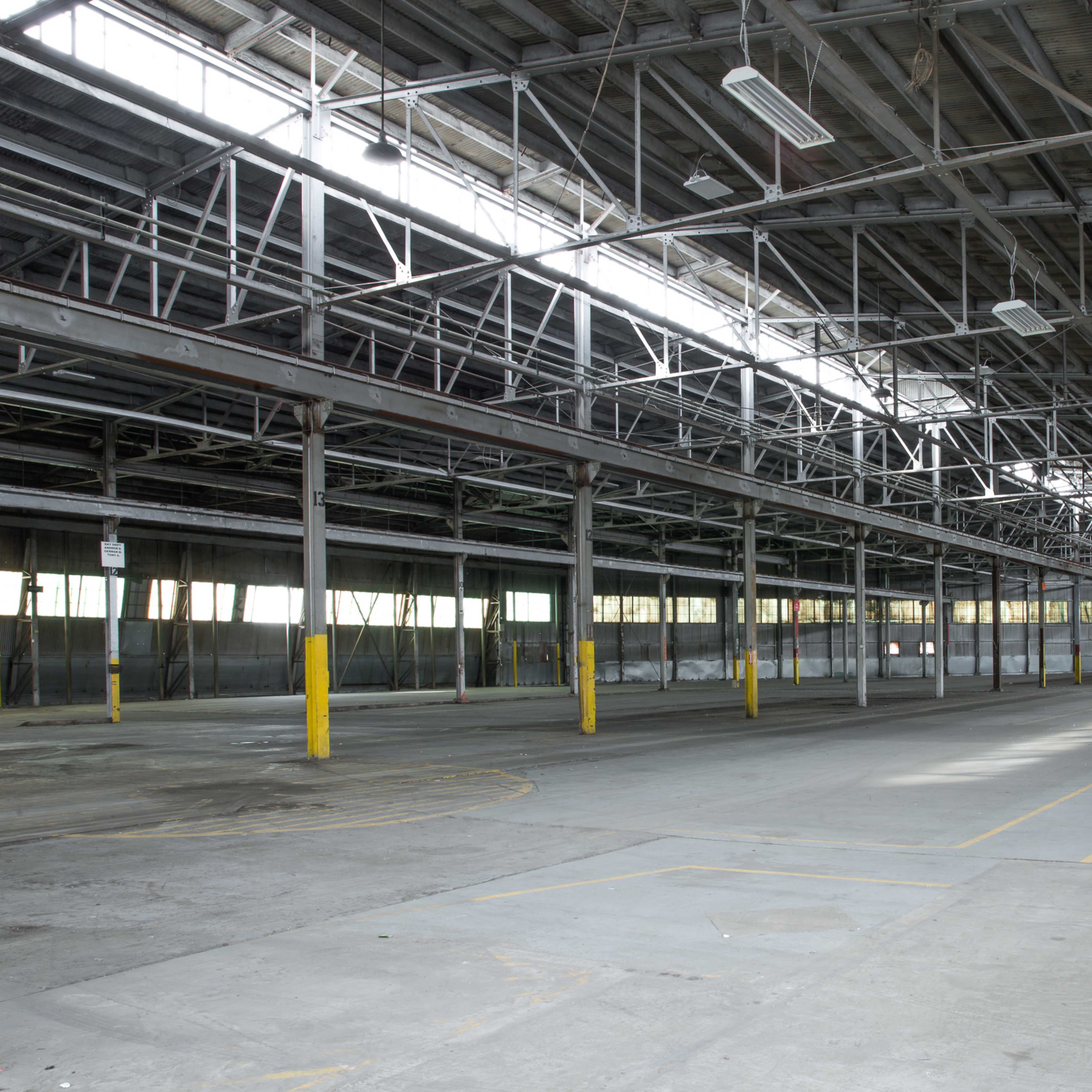 A large, empty industrial warehouse with high ceilings and a concrete floor.