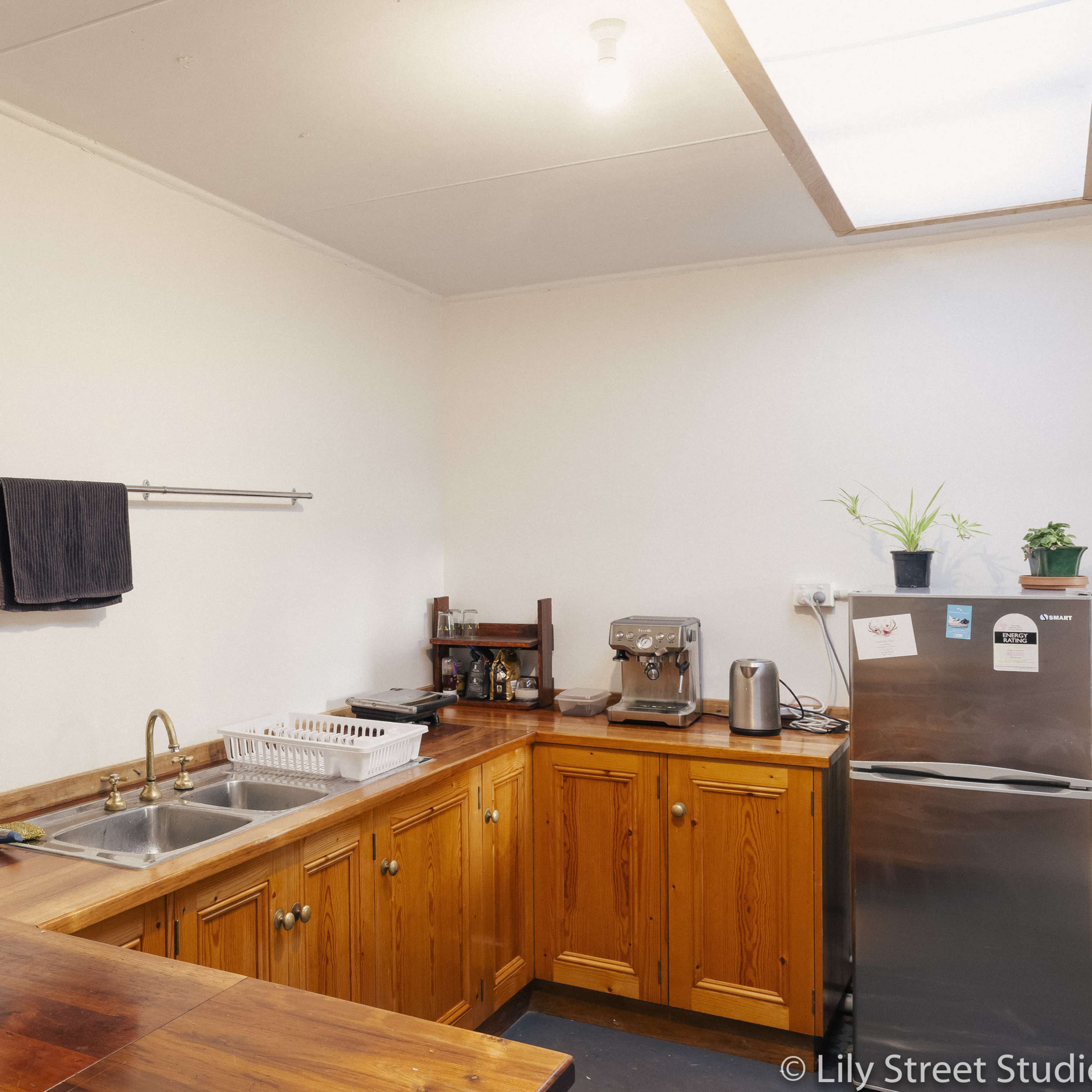A clean kitchen with wooden cabinets, a double sink, a countertop with a microwave, and various kitchen appliances.
