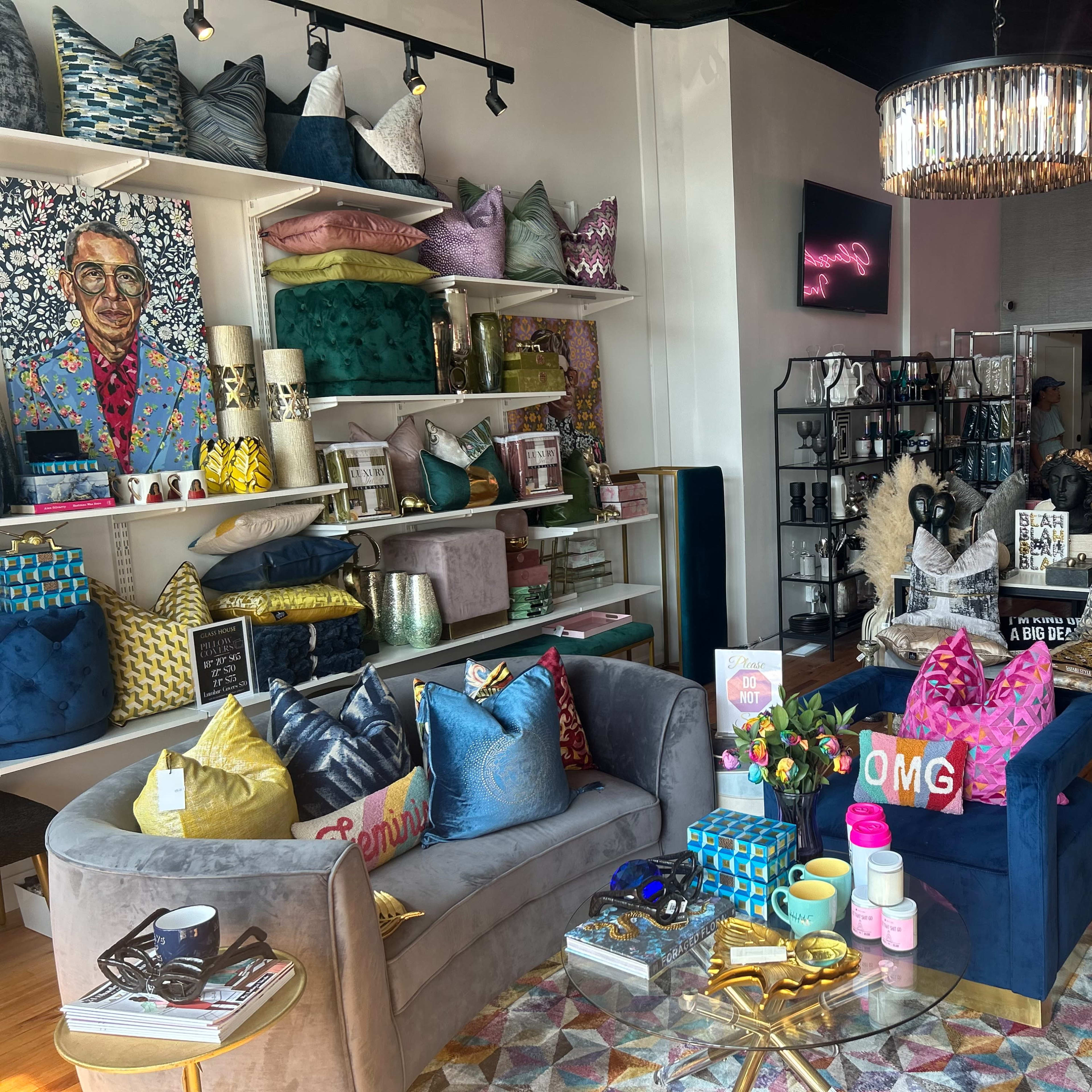 A vibrant interior home decor store displaying colorful throw pillows, artwork, and decorative items on shelves and tables.