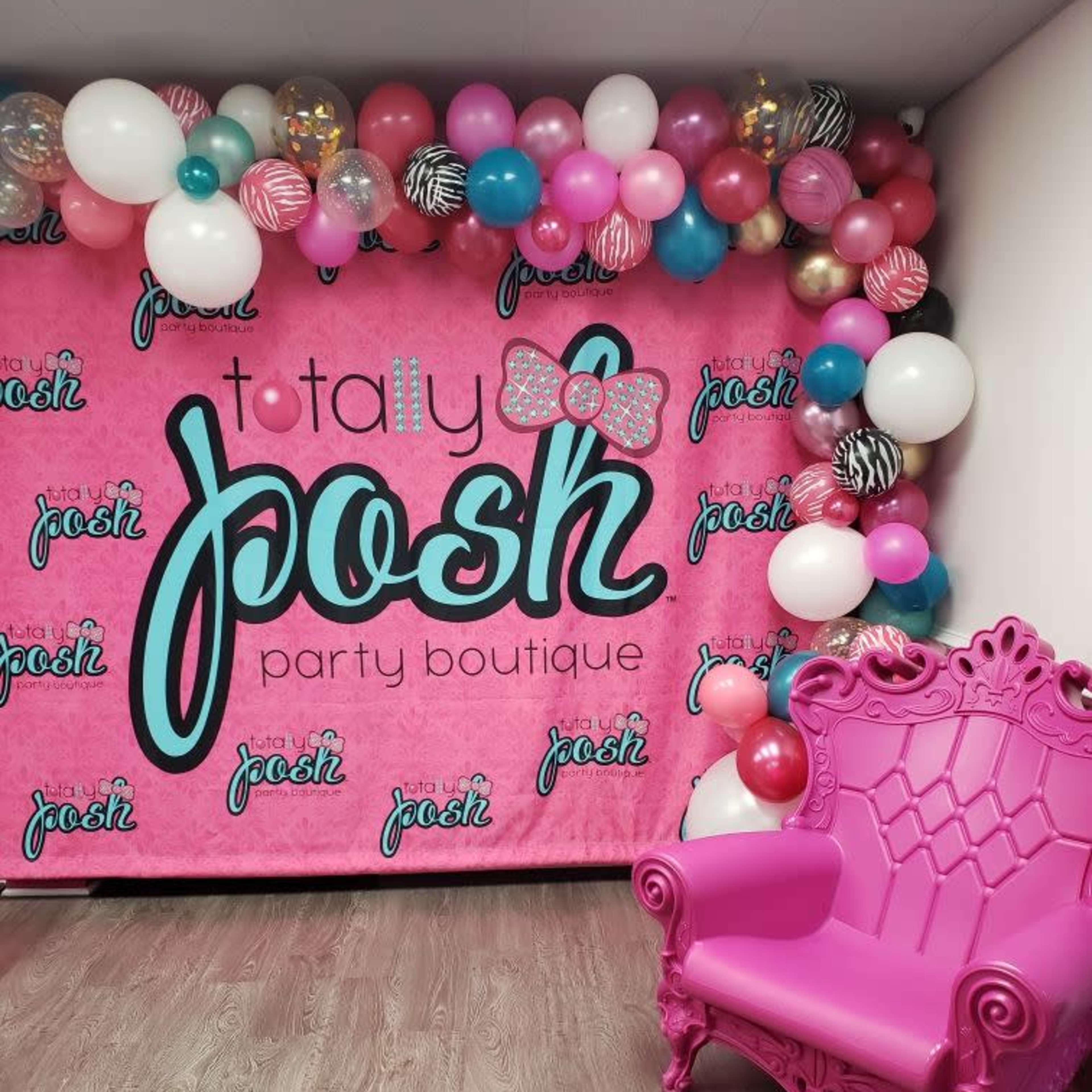 A vibrant party backdrop with balloons in pink, white, and black, alongside a bright pink chair.
