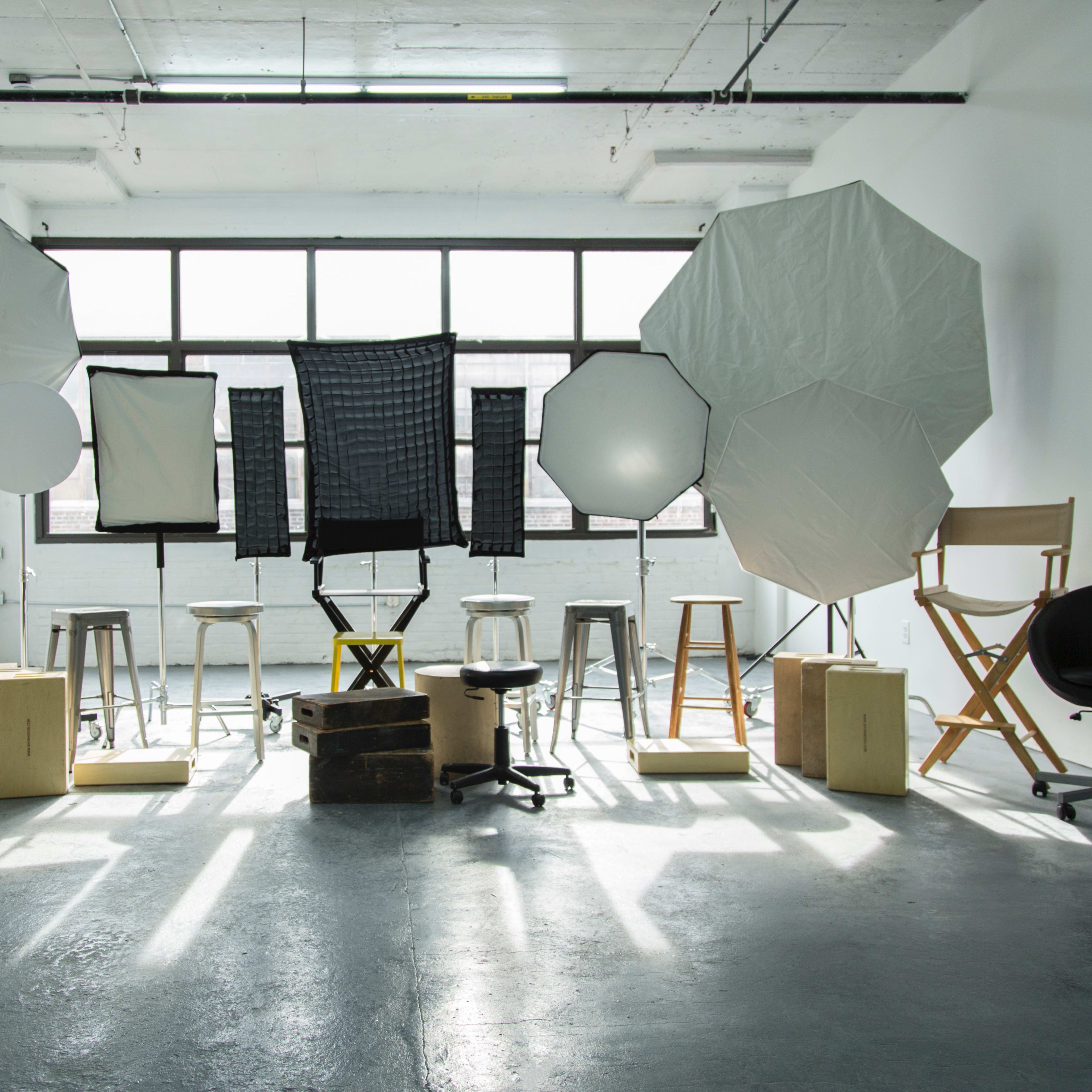 A photography studio is arranged with various lighting equipment and seating positioned around a central area.