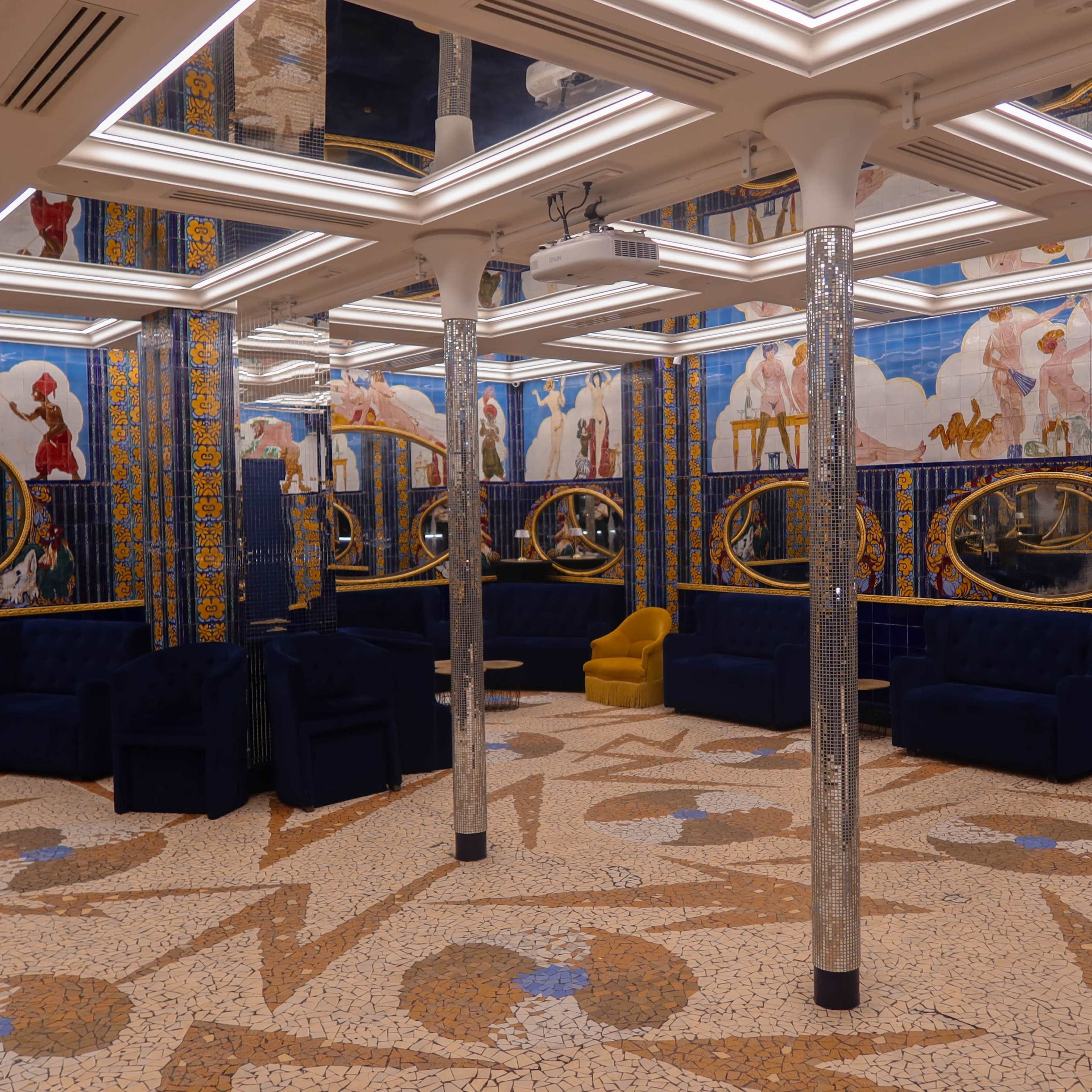 A decorative room featuring multiple circular mirrors, blue seating, and an ornate tiled floor with artistic patterns.