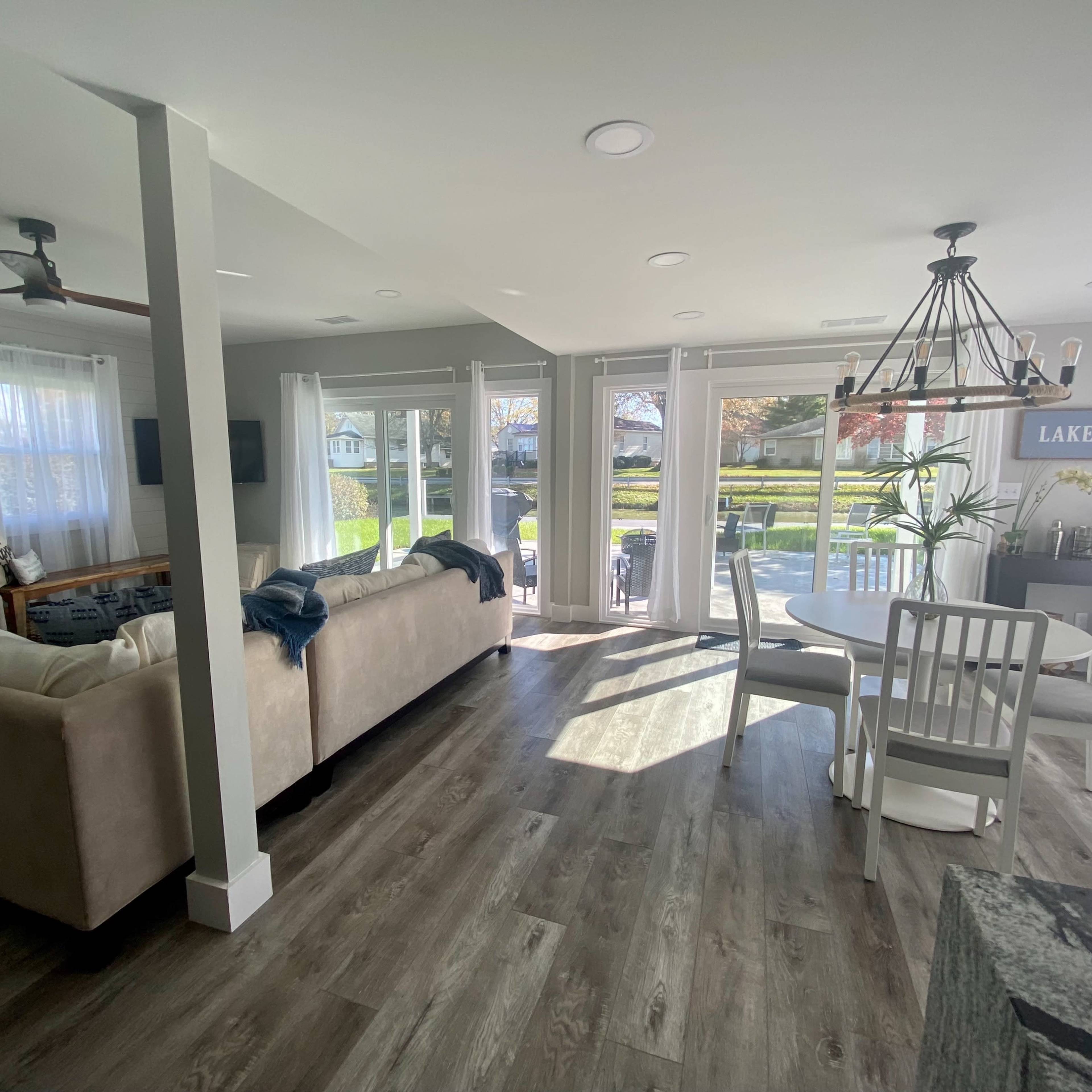 A bright, open-concept living area with a sofa, dining table, and large windows that provide a view of an outdoor patio.