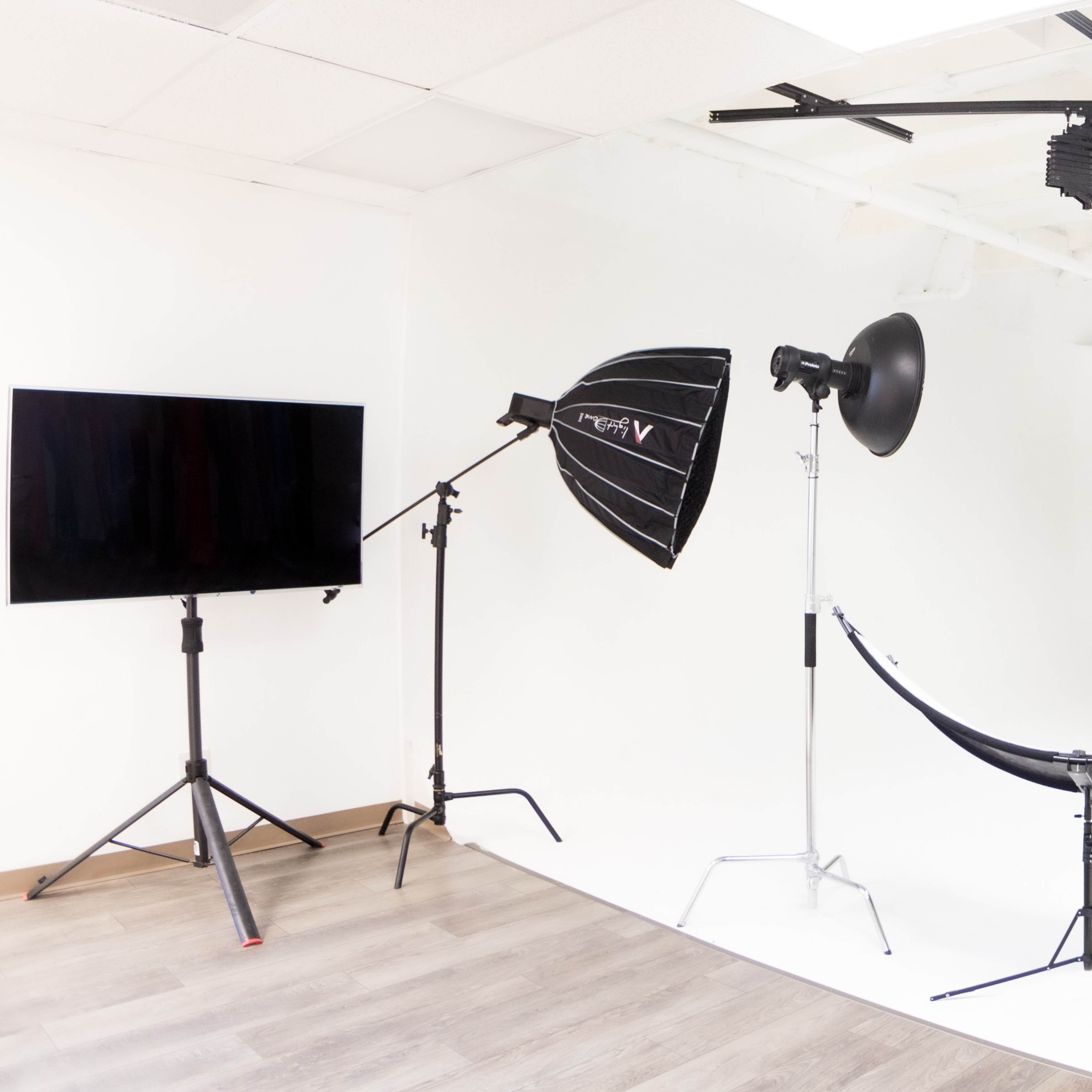 A photography studio setup with various lighting equipment arranged around a central stool on a white background.