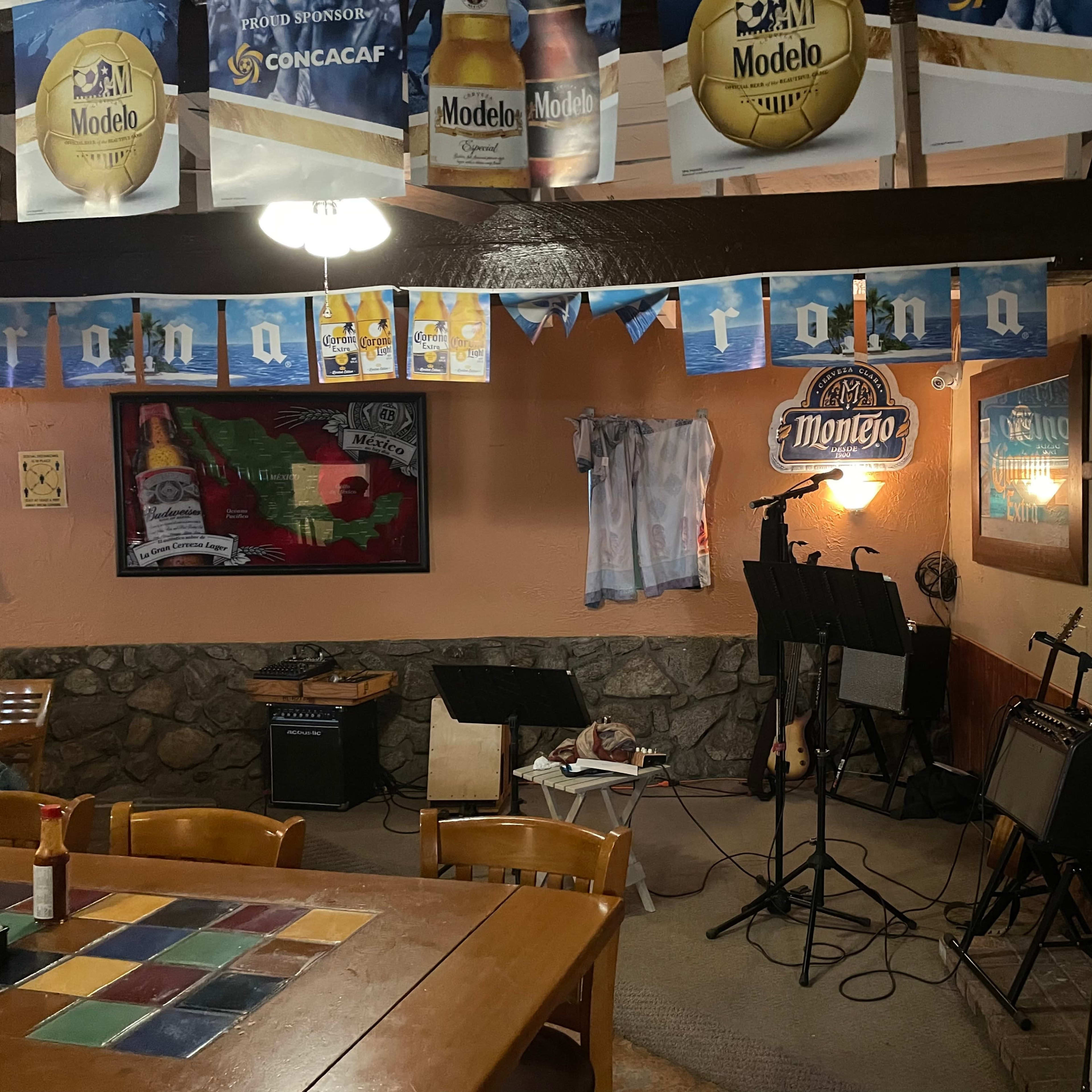 A rustic interior of a bar or restaurant featuring musical instruments, decorations, and various beer advertisements on the walls.