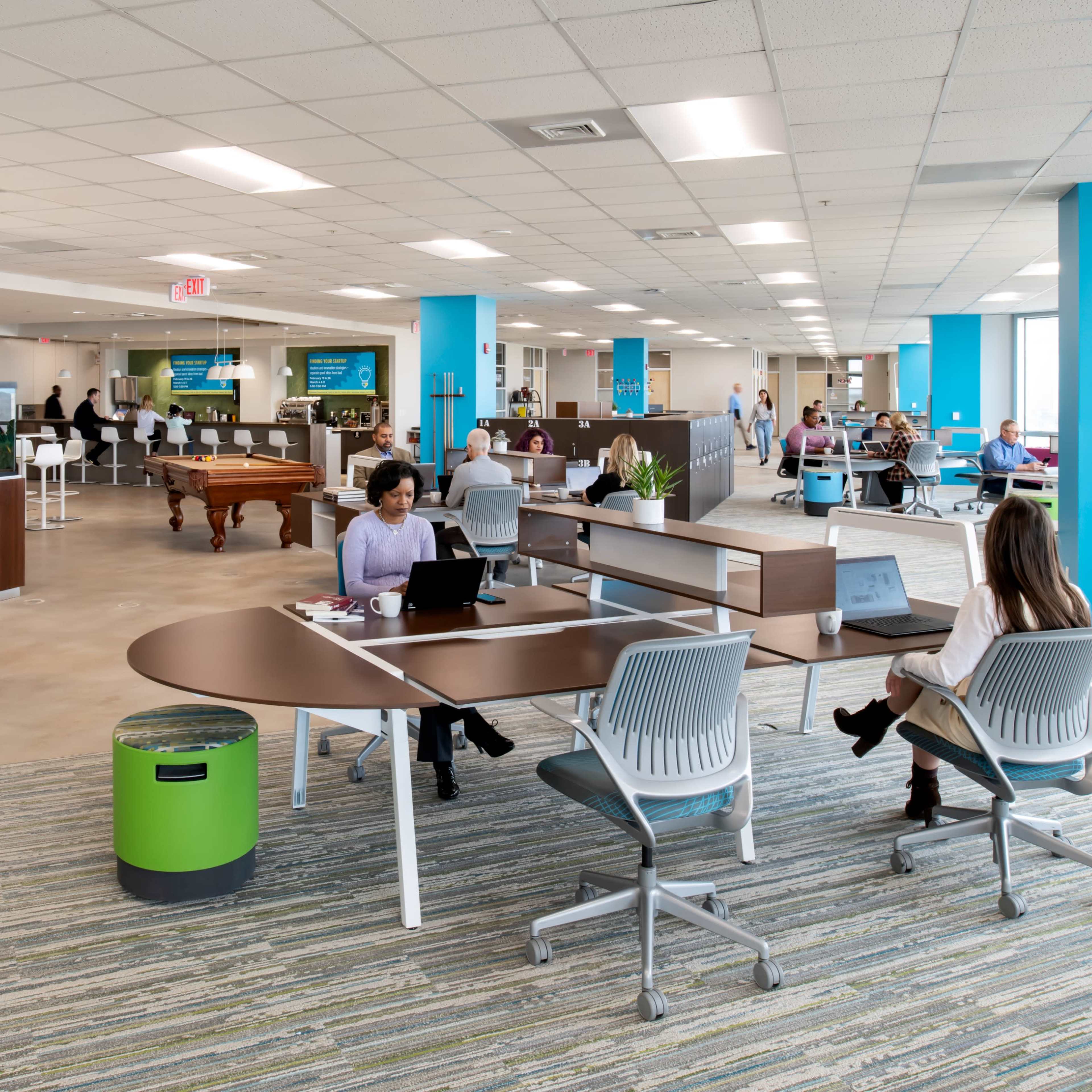 A modern office space with workstations, a recreational area featuring a pool table, and employees engaged in various activities.