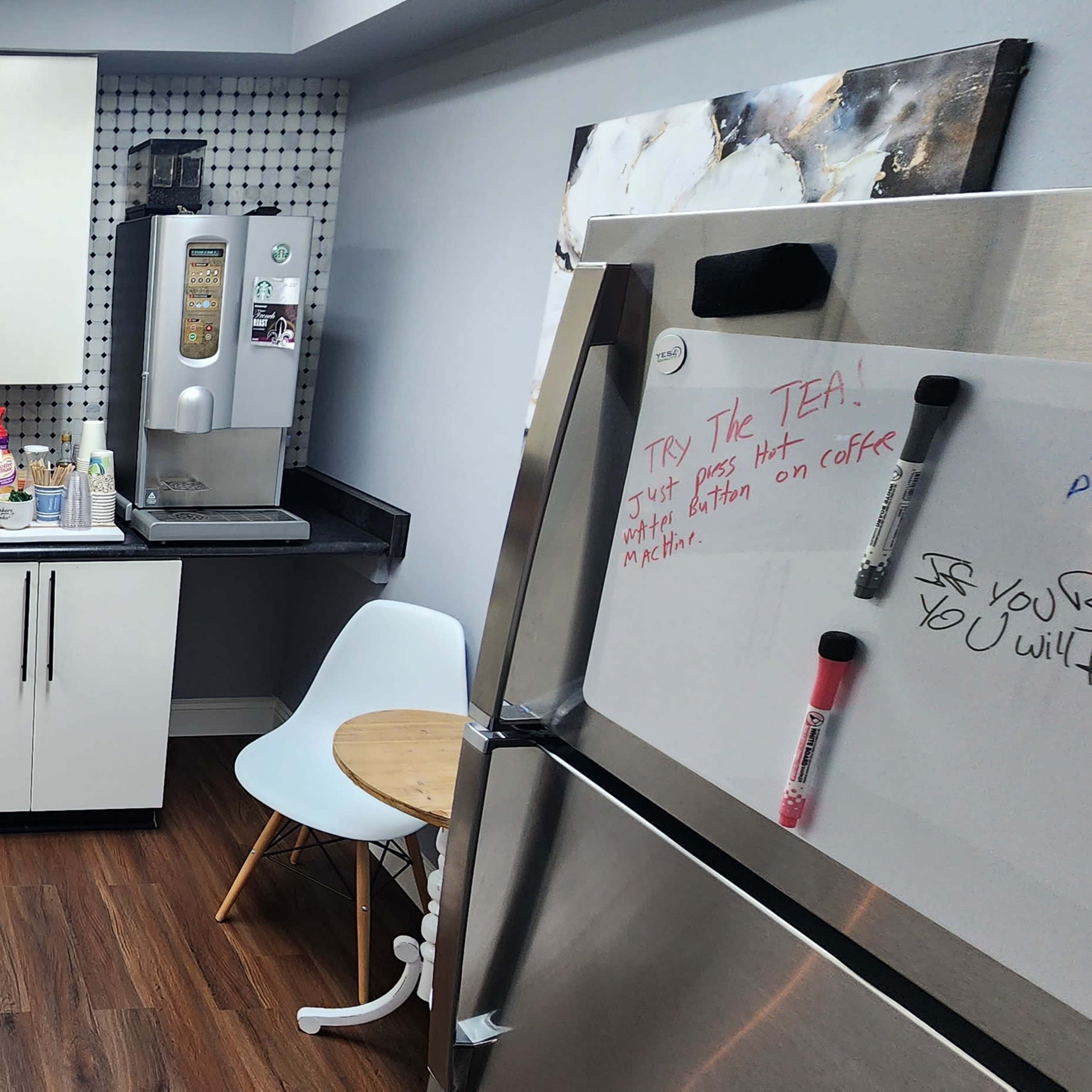 A compact kitchen with white cabinets, a dark countertop, a small dining table, and various kitchen appliances.