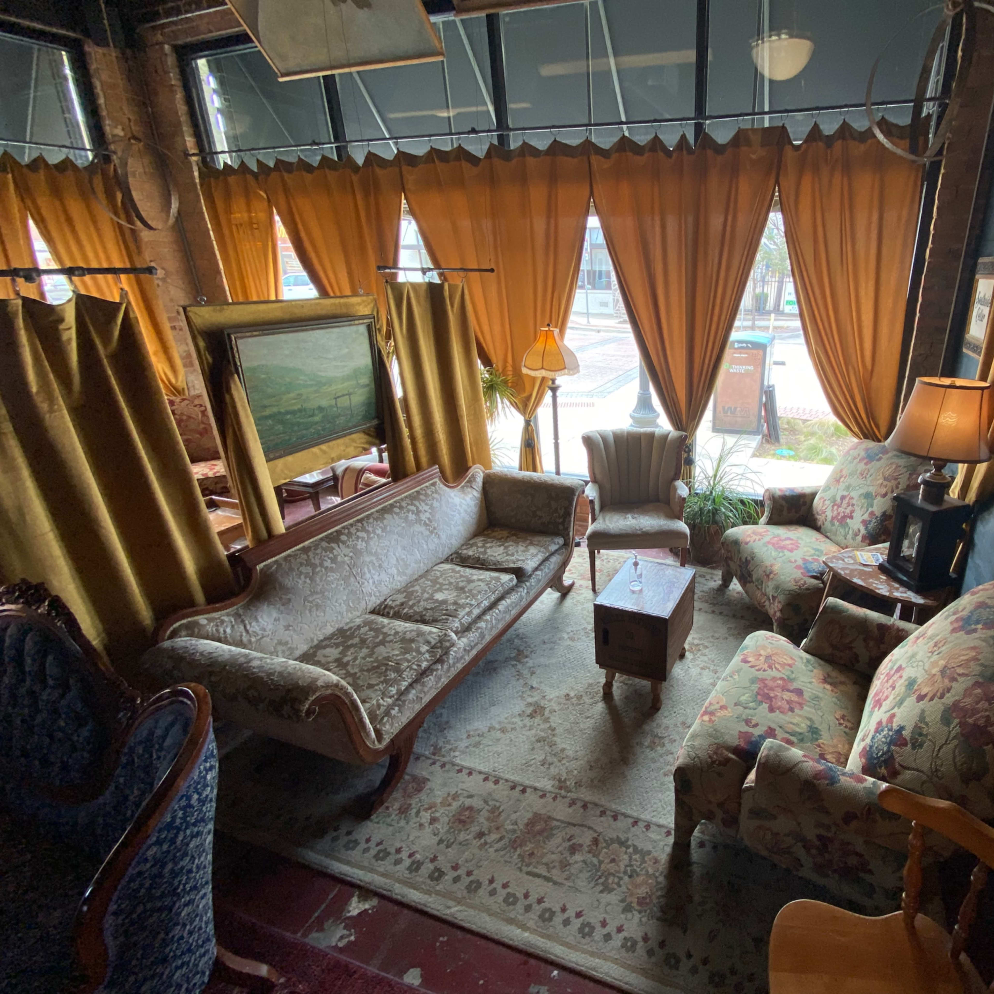 A cozy sitting area with floral-patterned furniture, warm curtains, and a rug on the floor.