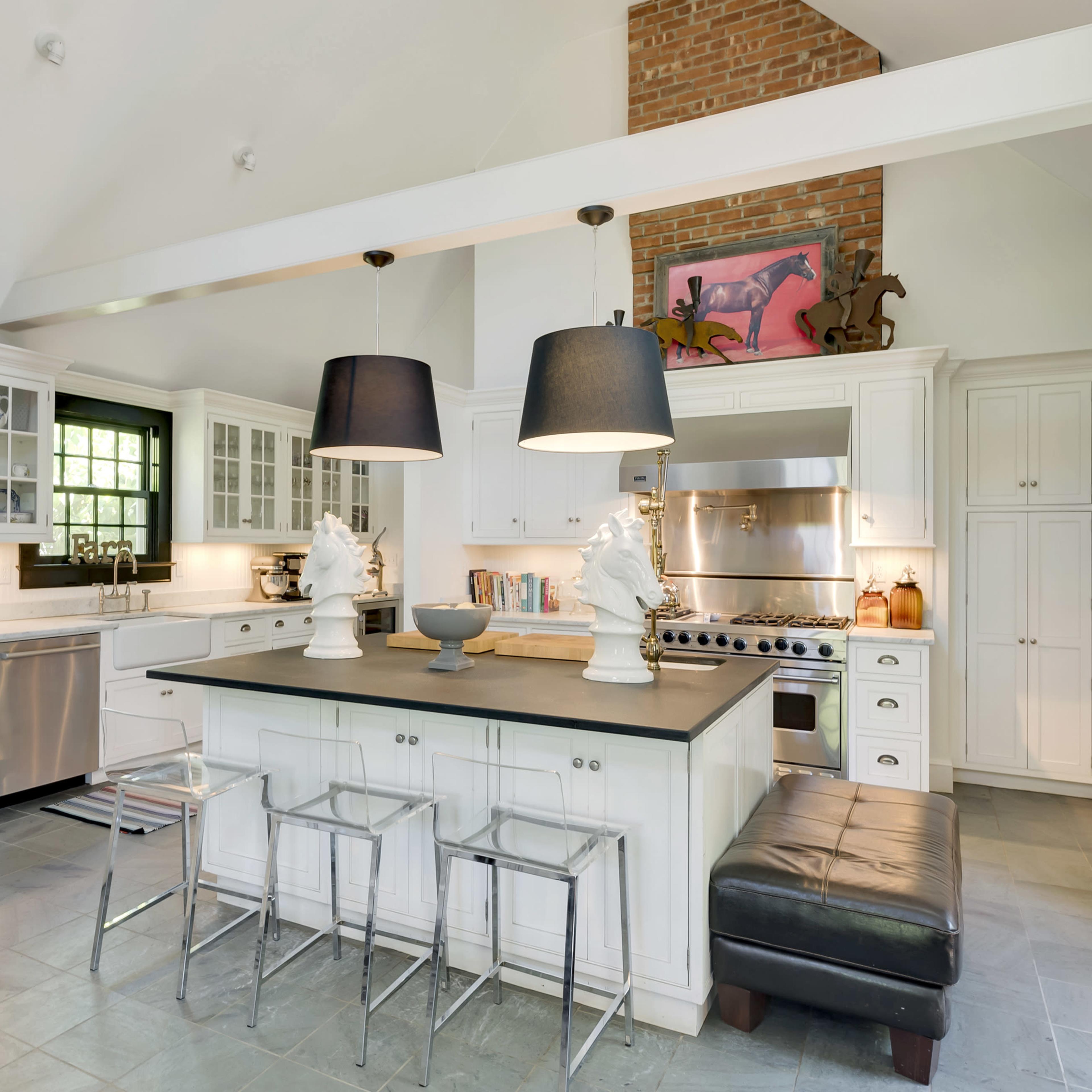 The kitchen features white cabinetry, a large central island with black countertops, and two pendant lights hanging overhead.